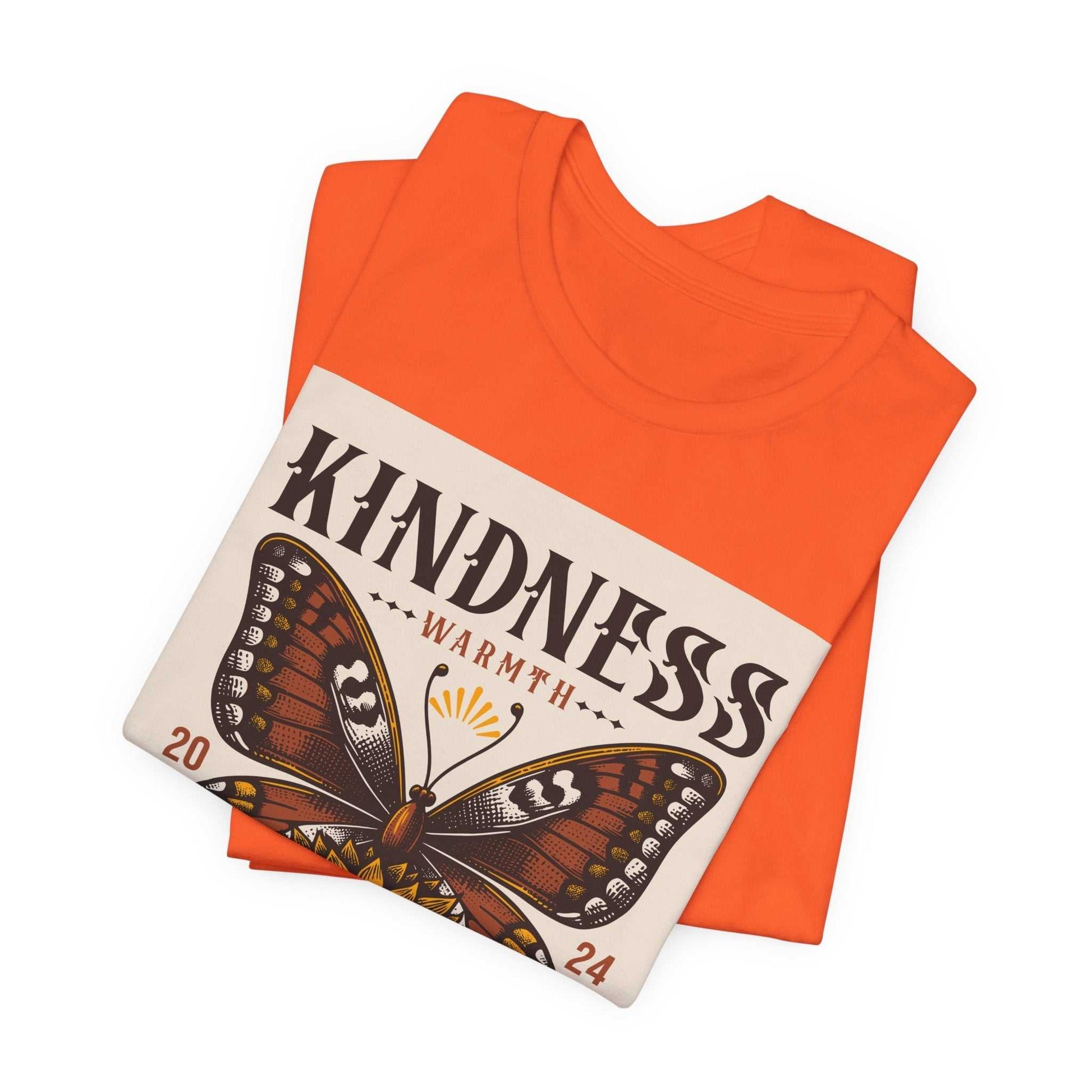 Folded orange Kindness Butterfly Tee with butterfly and sunflower design and kindness message on front
