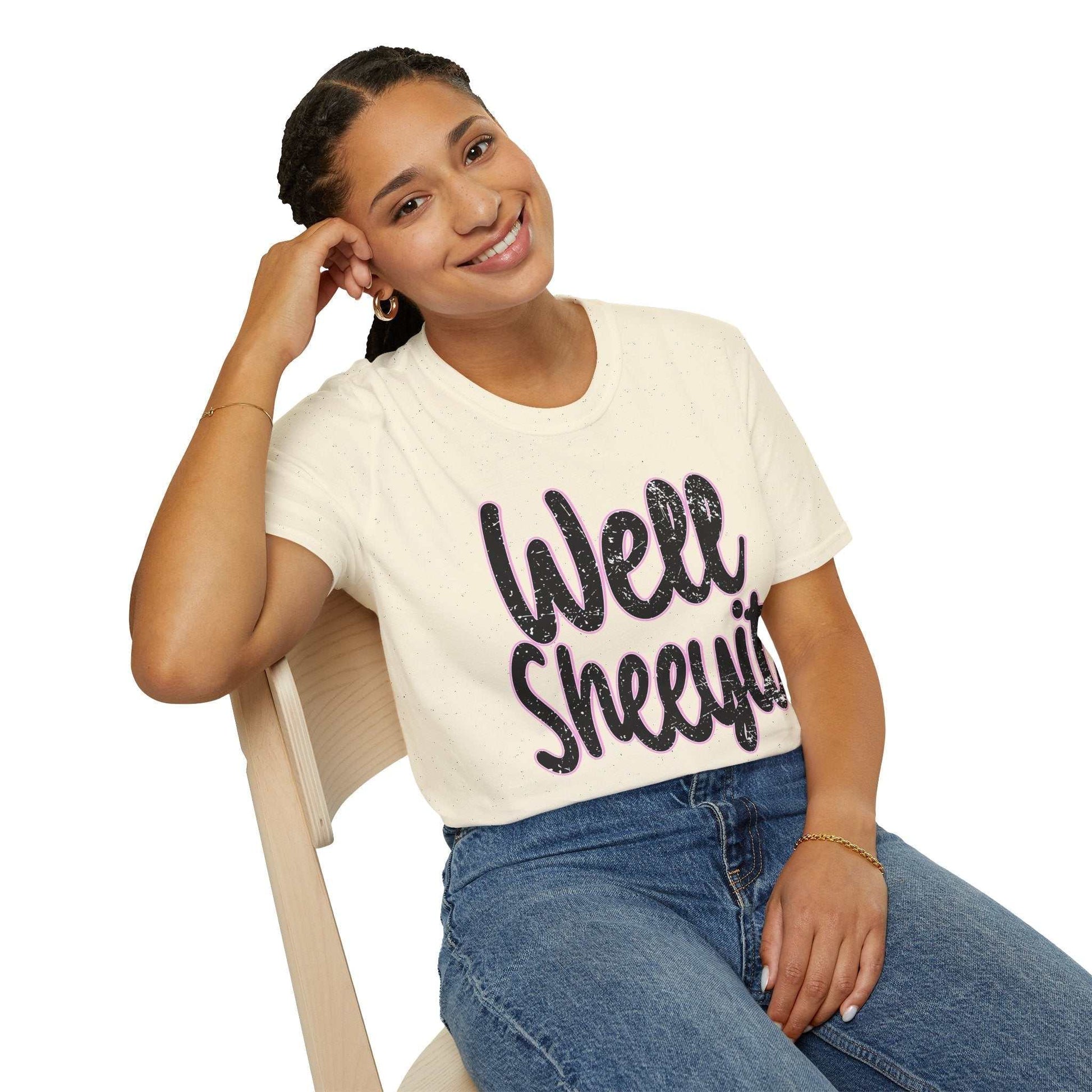 Woman wearing casual statement tee white t-shirt with funny "Well Sheeyit" quote sitting on wooden chair smiling