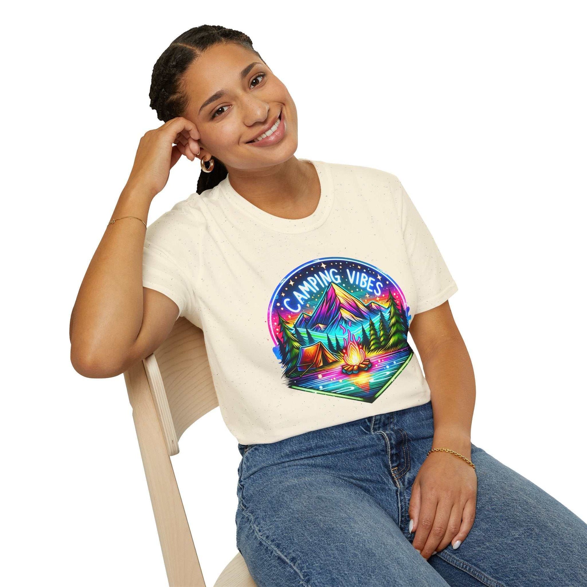 Woman wearing Camping Vibes Unisex softstyle t-shirt with colorful camping graphic sitting on chair smiling