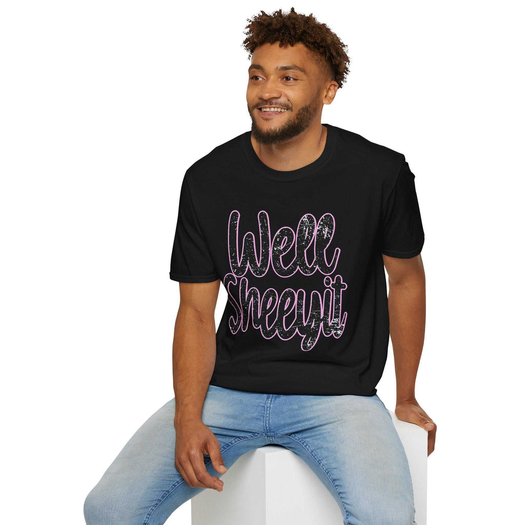 Man wearing black casual statement tee with "Well Sheeyit" funny quote, paired with light blue jeans, sitting on white block