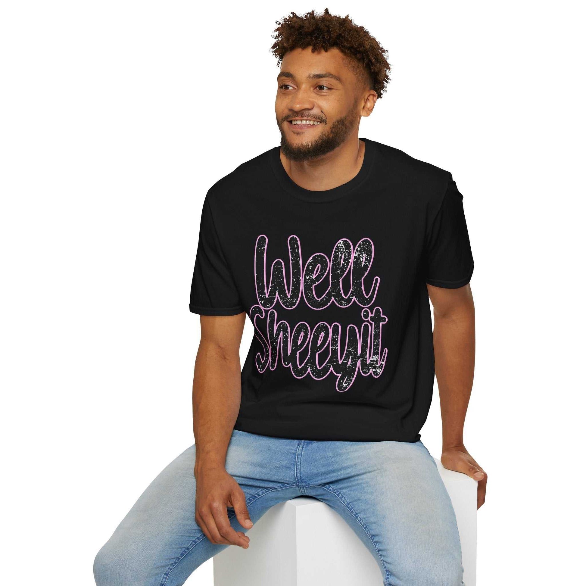 Man wearing black casual statement tee with "Well Sheeyit" funny quote, paired with light blue jeans, sitting on white block