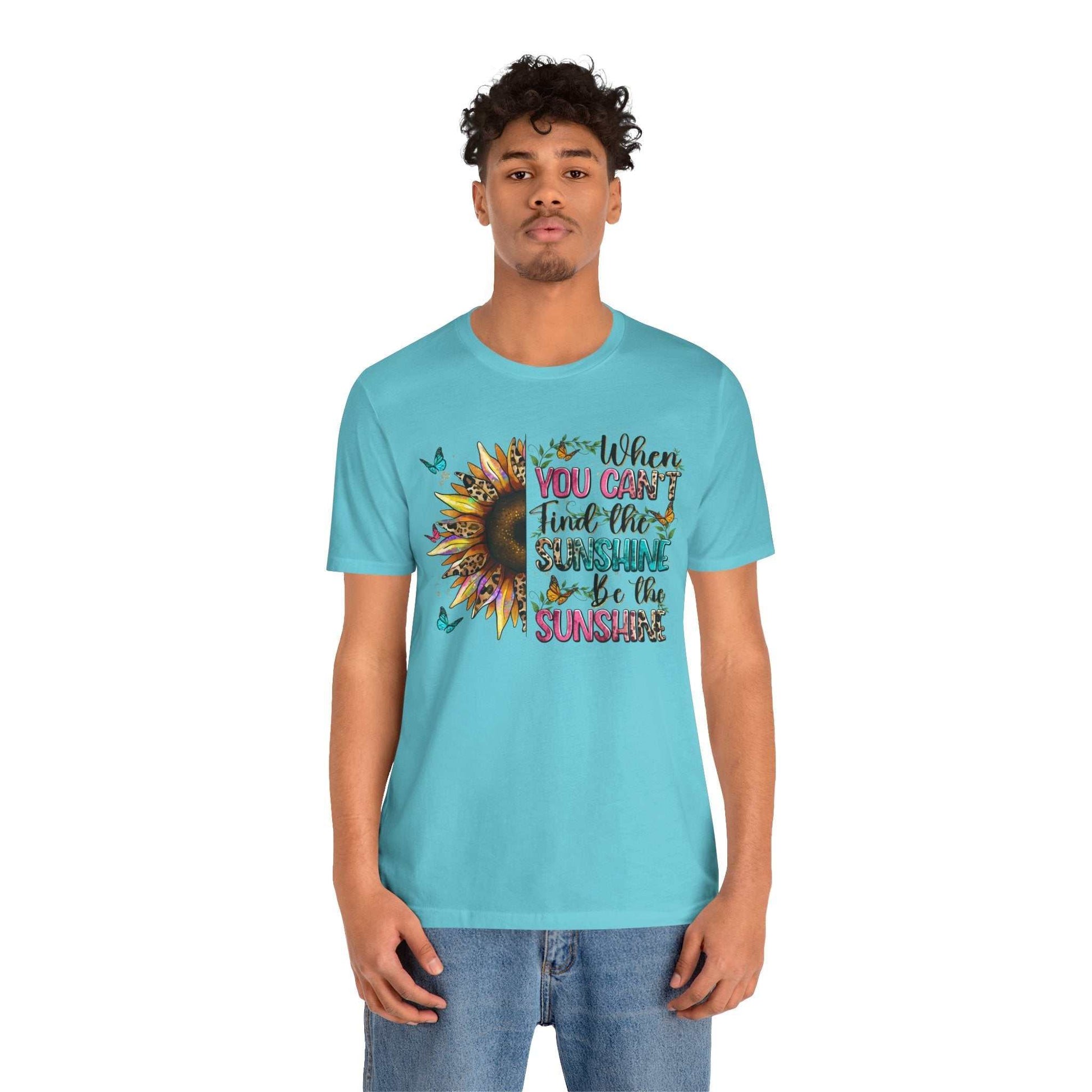 Man wearing a light blue Sunshine Quote Tee with a vibrant sunflower and text design encouraging positivity.