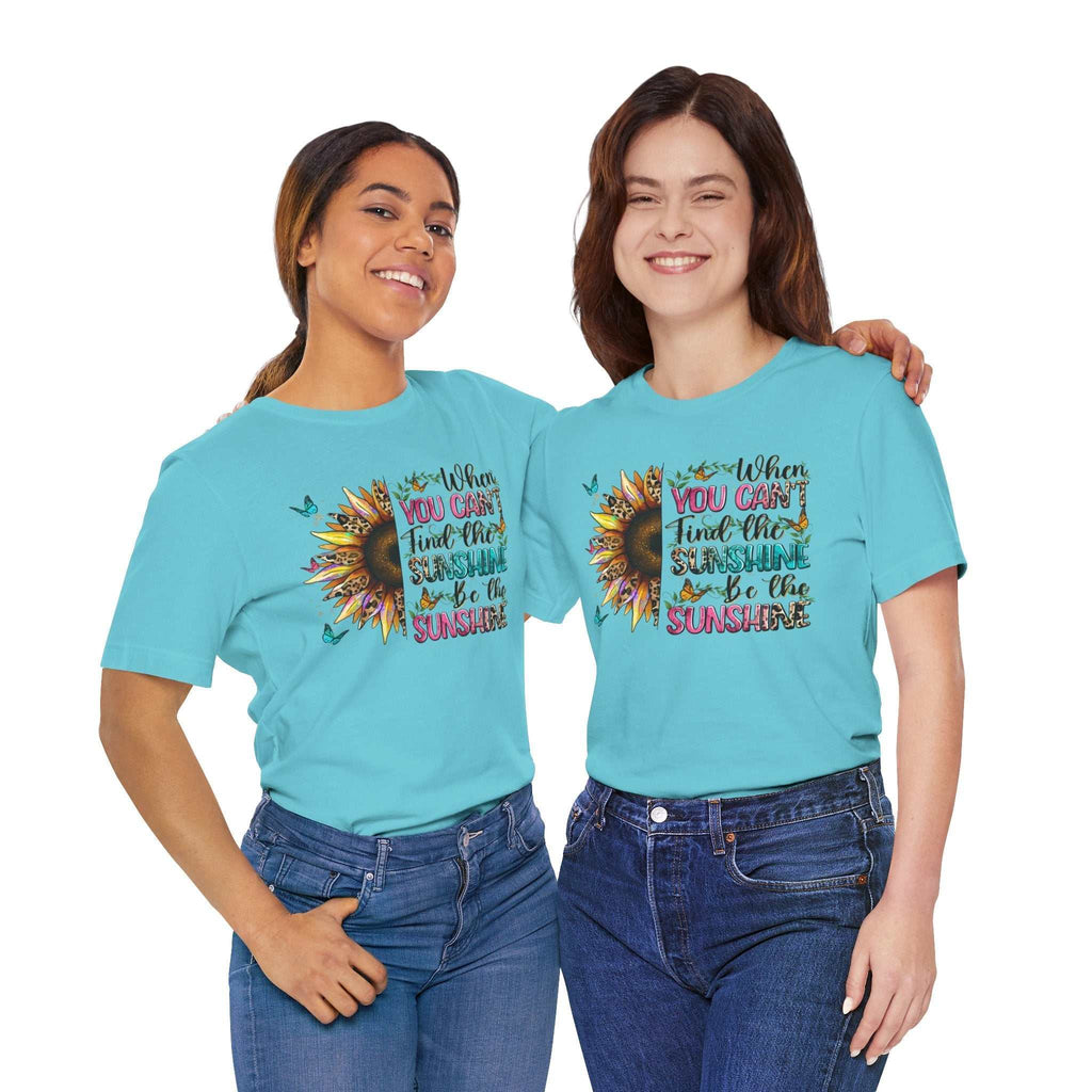 Two women wearing light blue Sunshine Quote Tee with colorful sunflower and inspirational text design, paired with jeans