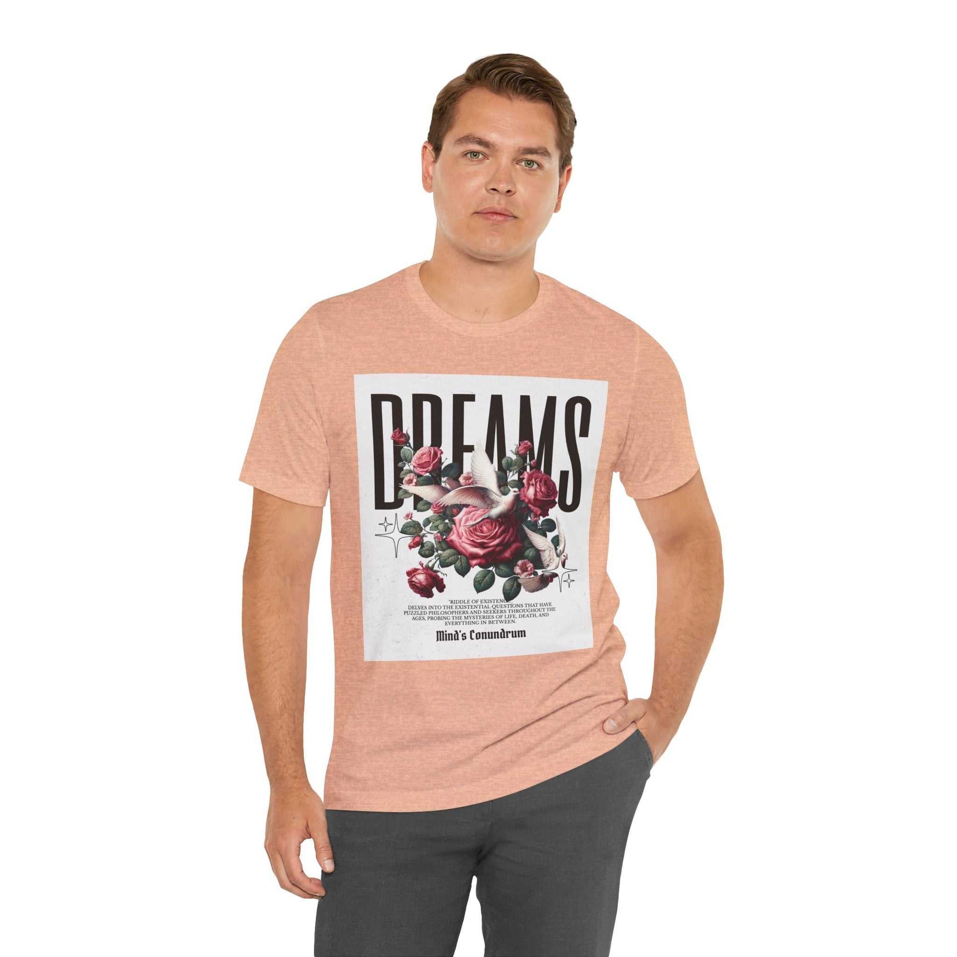 Man wearing a peach Dreams Floral Tee with a bold floral graphic and "DREAMS" text on the front, styled with casual dark pants.