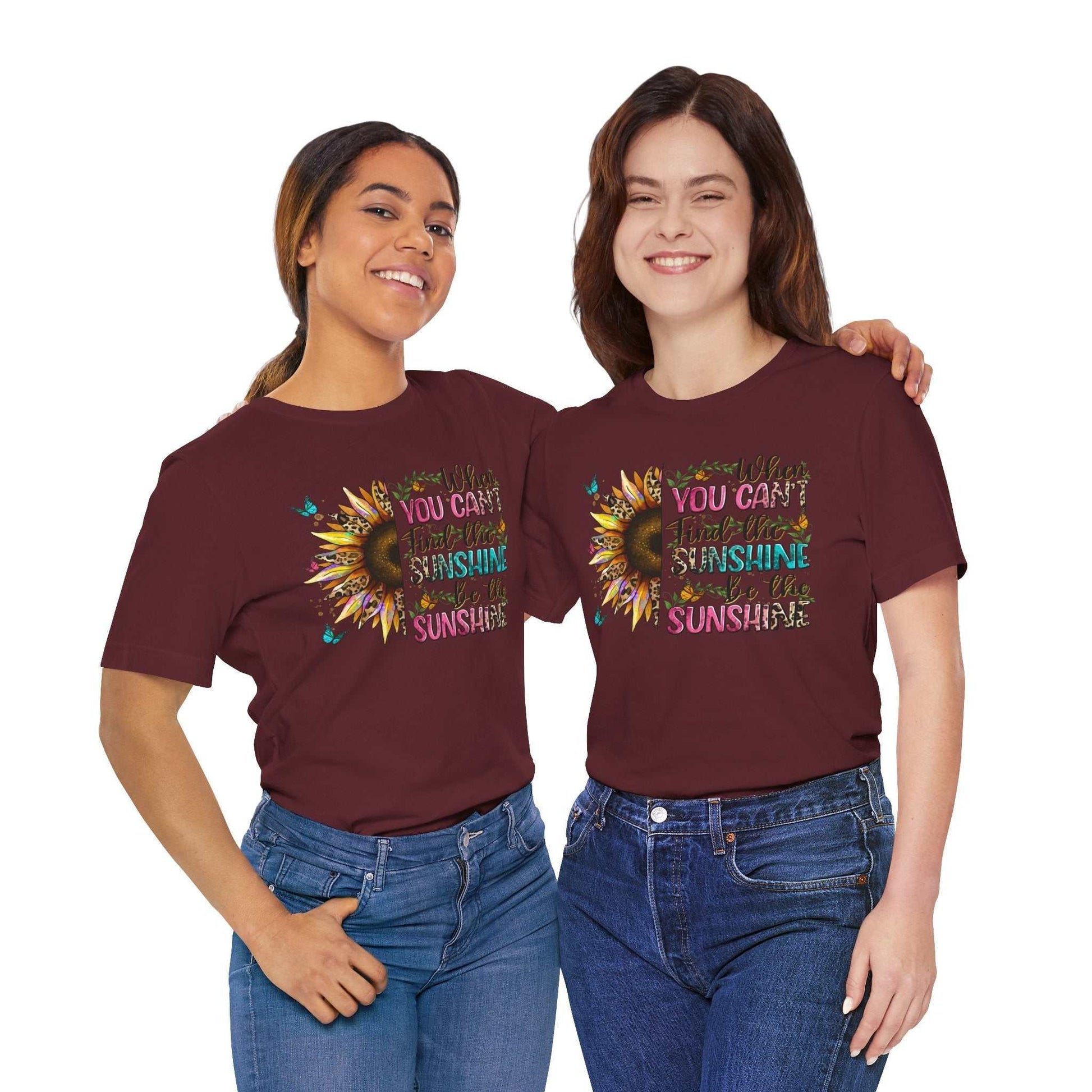 Two women wearing maroon Sunshine Quote Tees with colorful sunflower graphic and inspirational text, smiling and posing together