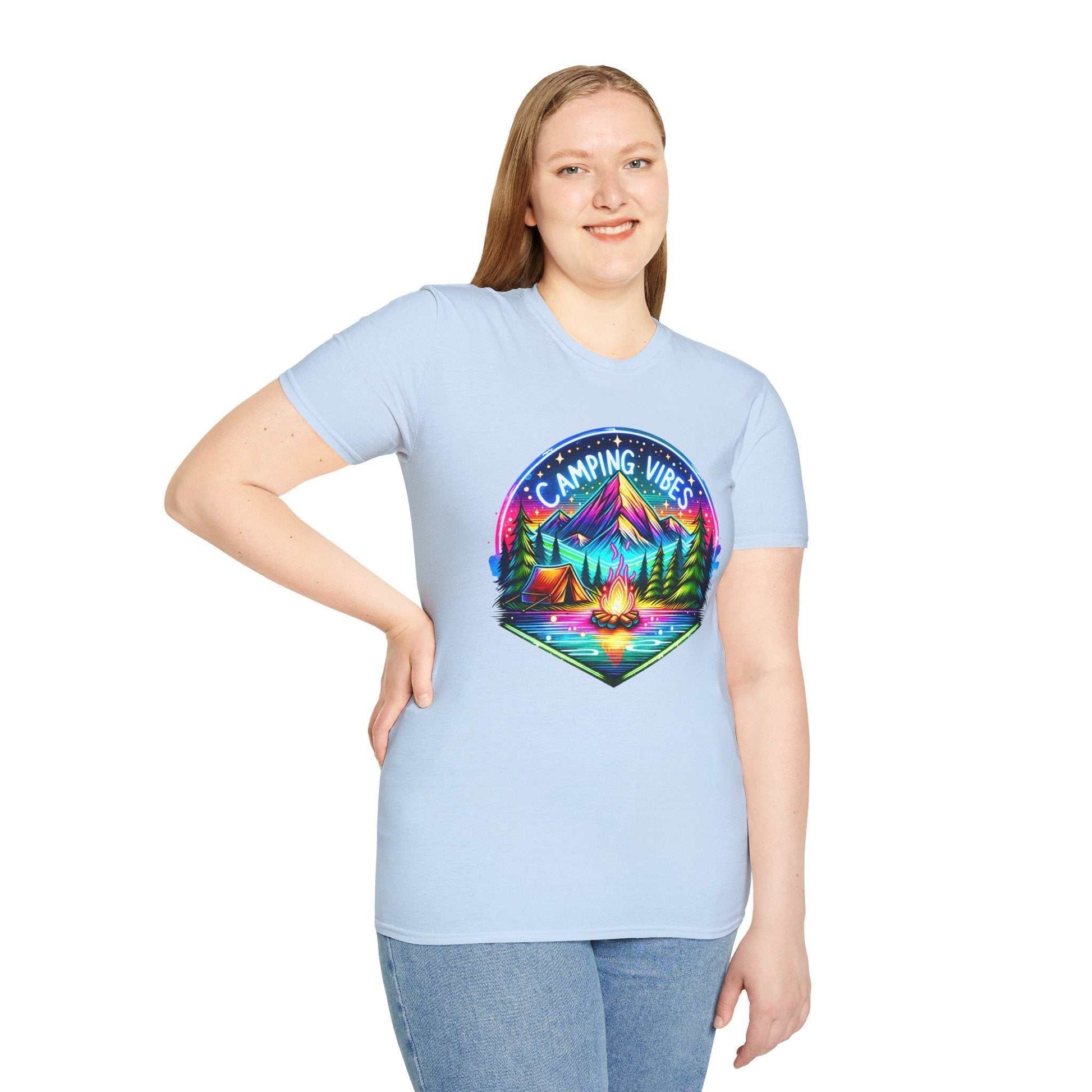 Unisex softstyle t-shirt in light blue featuring a colorful "Camping Vibes" graphic with mountains, trees, tents, and a campfire.