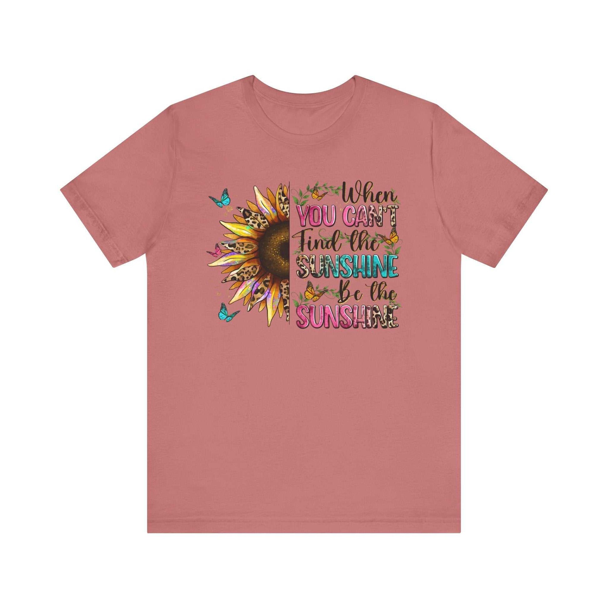 Unisex pink tee with sunflower and butterfly design featuring quote "When you can't find the sunshine be the sunshine"