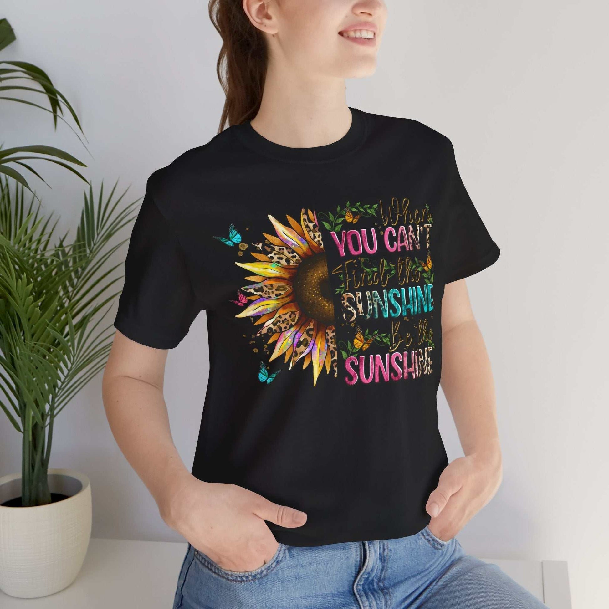 Woman wearing black Sunshine Quote Tee with colorful sunflower and positive text design