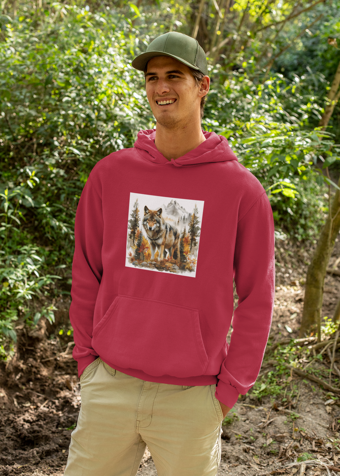 Man wearing a red Wilderness Wolf Hoodie with wolf and mountain graphic in forest setting
