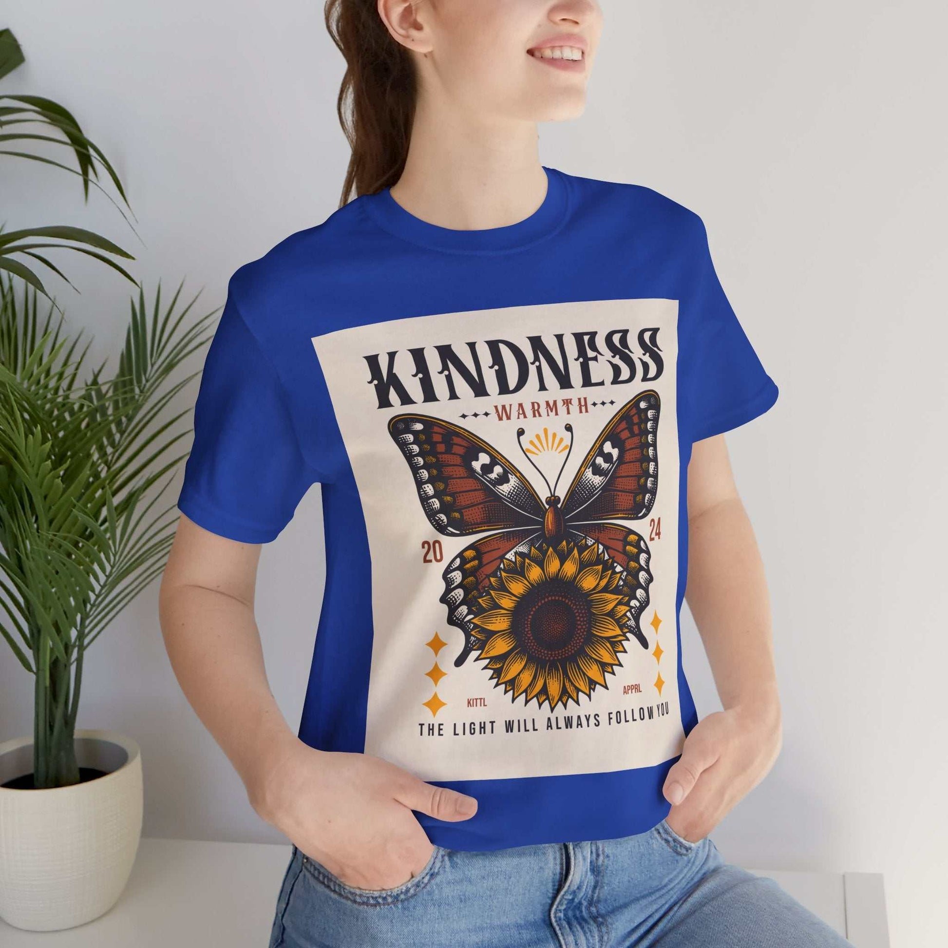 Woman wearing a royal blue Kindness Butterfly Tee with butterfly and sunflower graphic and positive message.