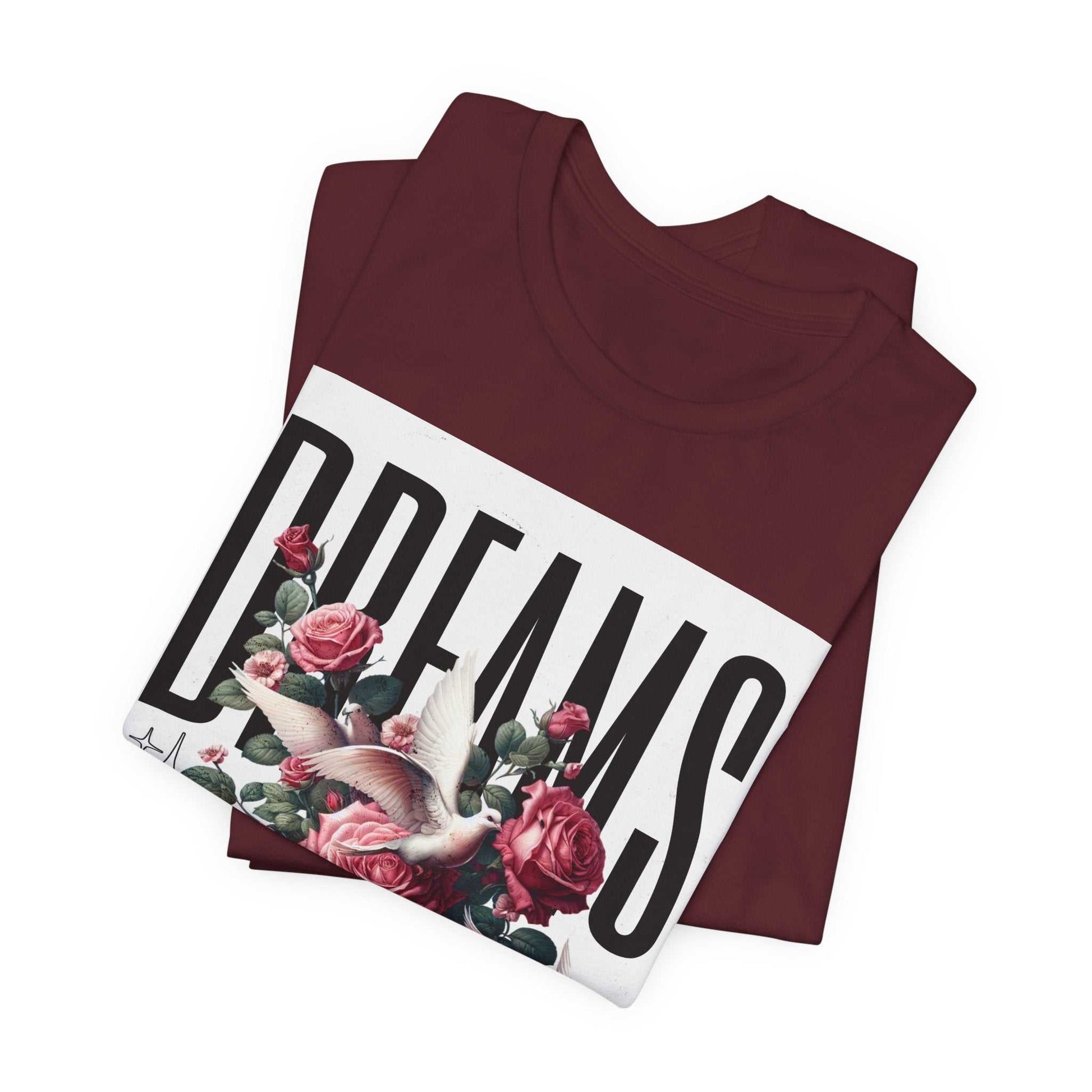 Folded maroon Dreams Floral Tee with bold white graphic text and floral design featuring roses and a dove