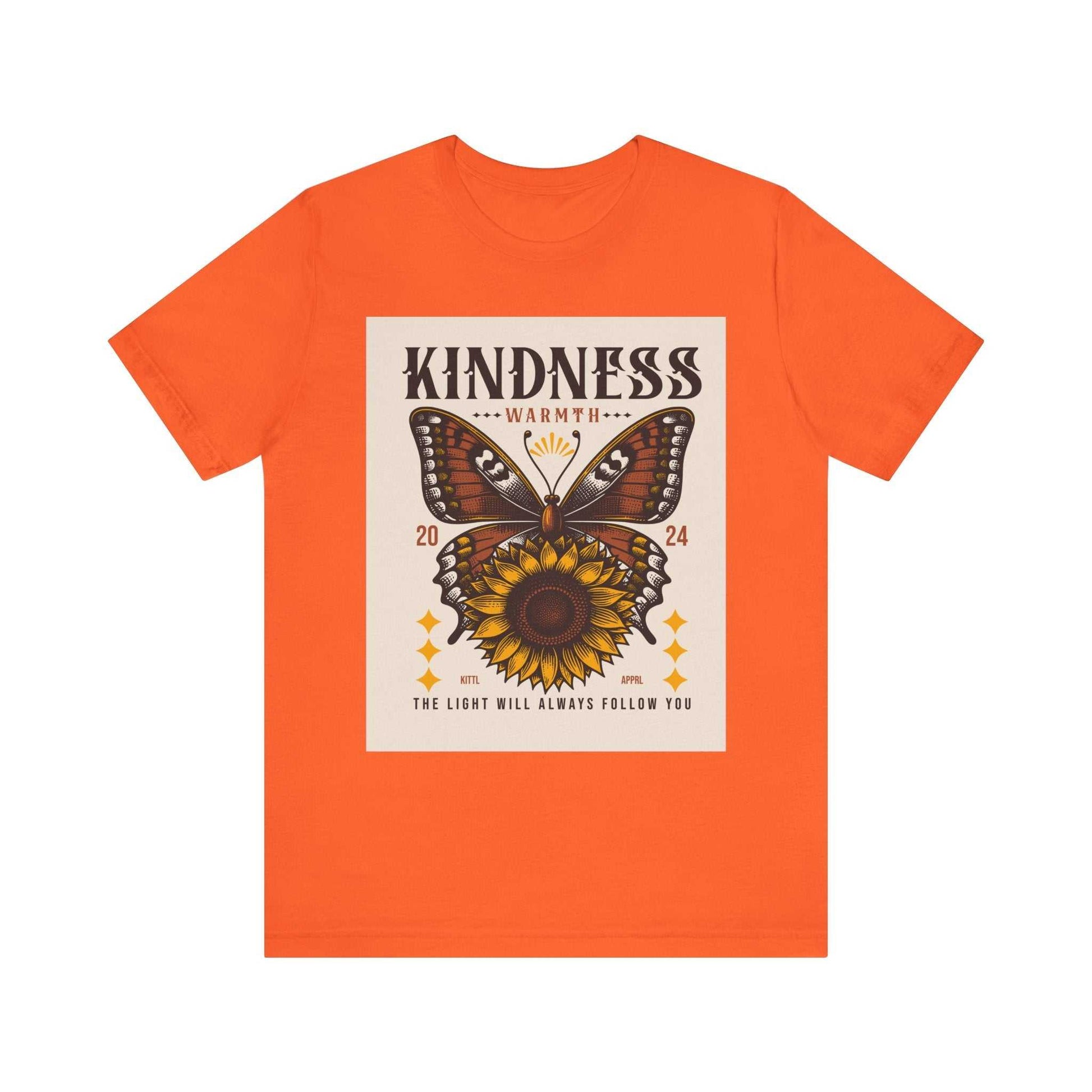Orange unisex Kindness Butterfly Tee featuring a butterfly and sunflower design with the text "Kindness Warmth" and "The light will always follow you" on the front.