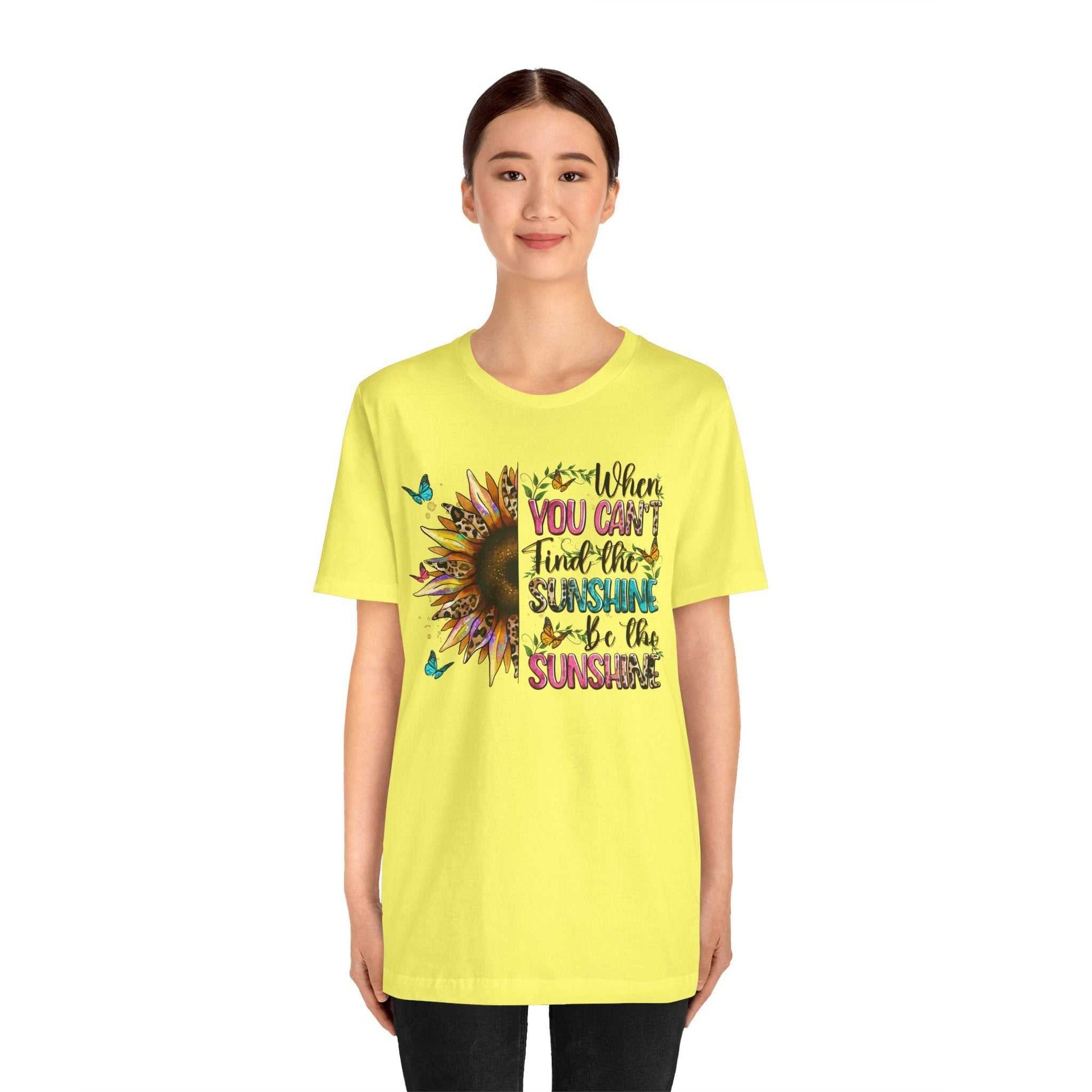Woman wearing yellow Sunshine Quote Tee with colorful sunflower and butterfly design and inspirational text on front