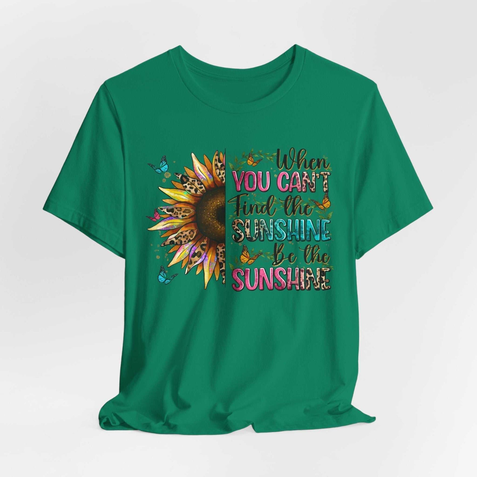 Green unisex t-shirt with half sunflower and colorful "When you can't find the sunshine be the sunshine" quote design.