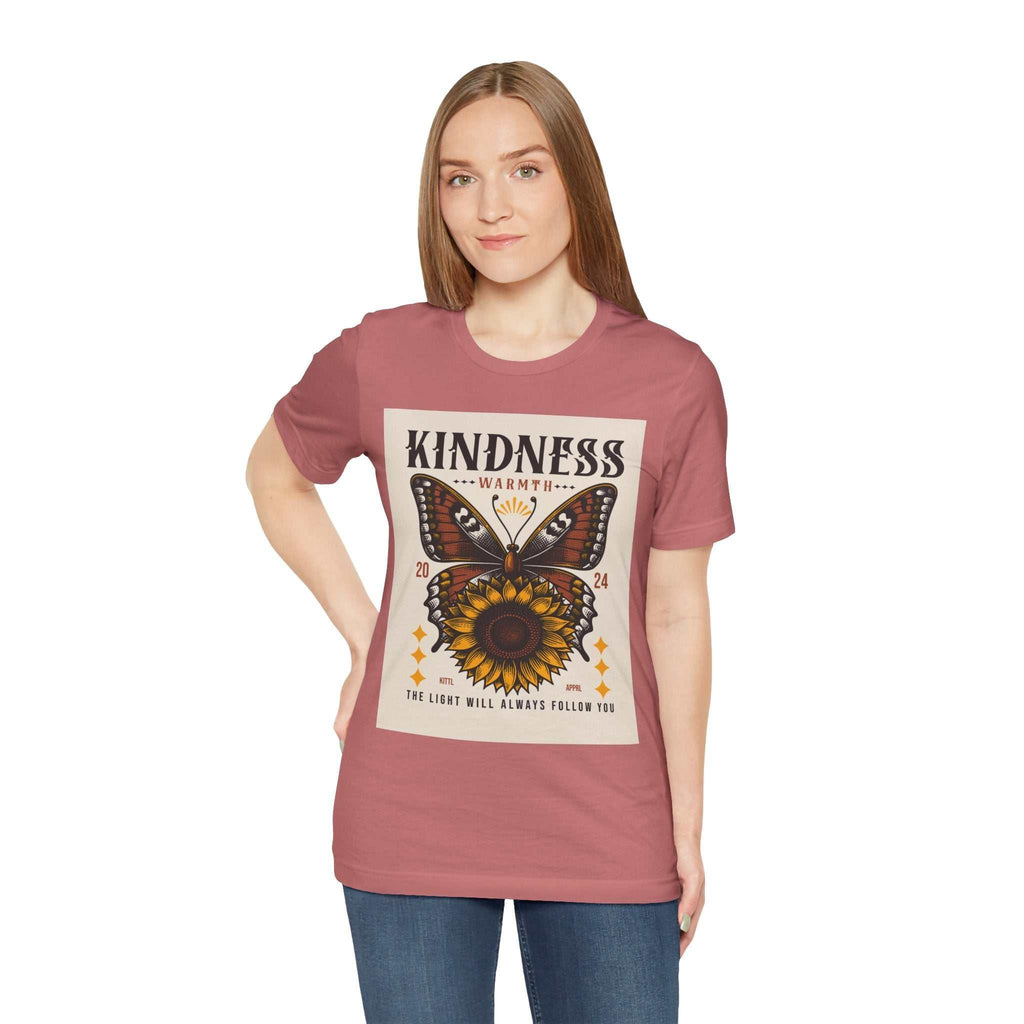 Woman wearing a Kindness Butterfly Tee with butterfly and sunflower design on dusty rose short sleeve shirt