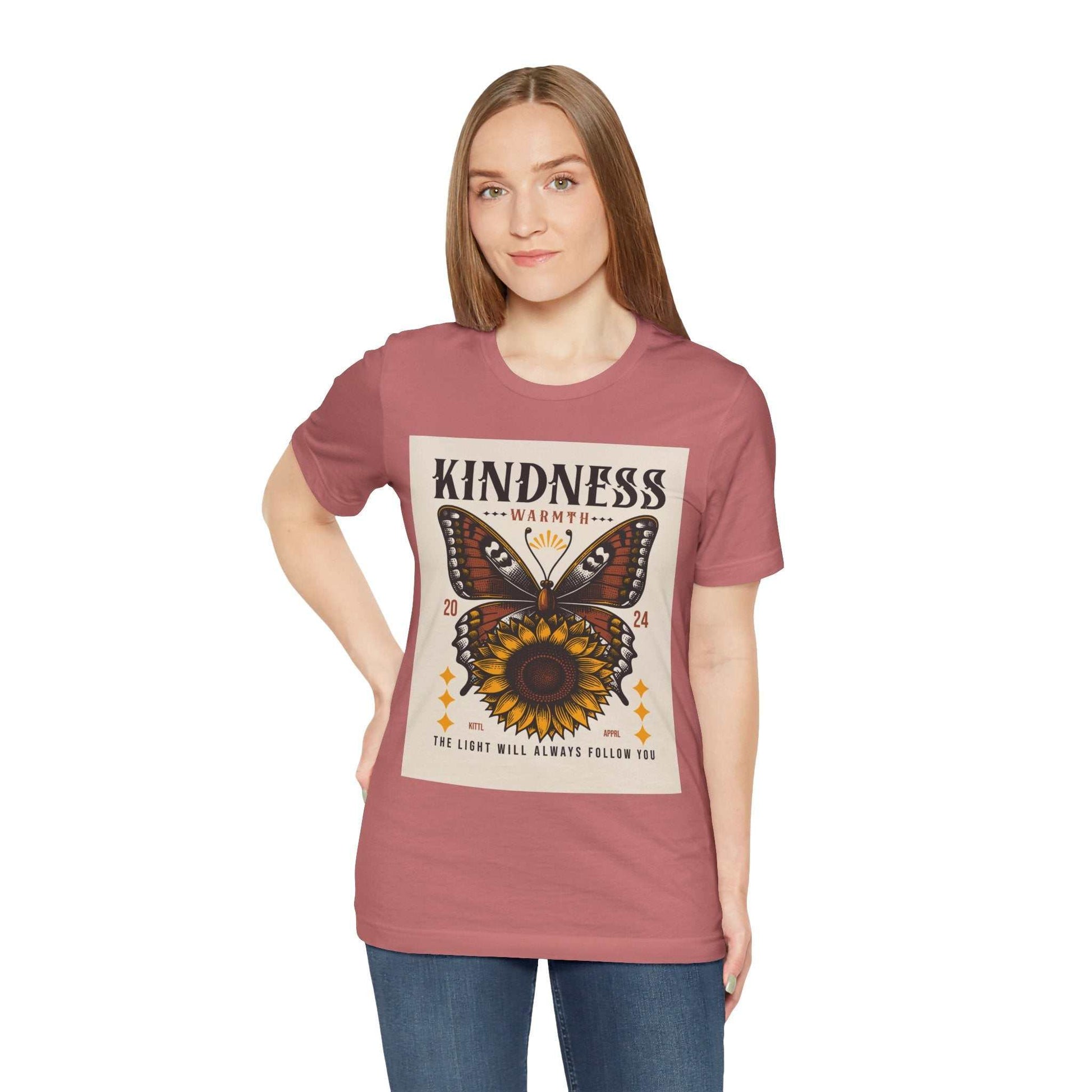 Woman wearing a Kindness Butterfly Tee with butterfly and sunflower design on dusty rose short sleeve shirt