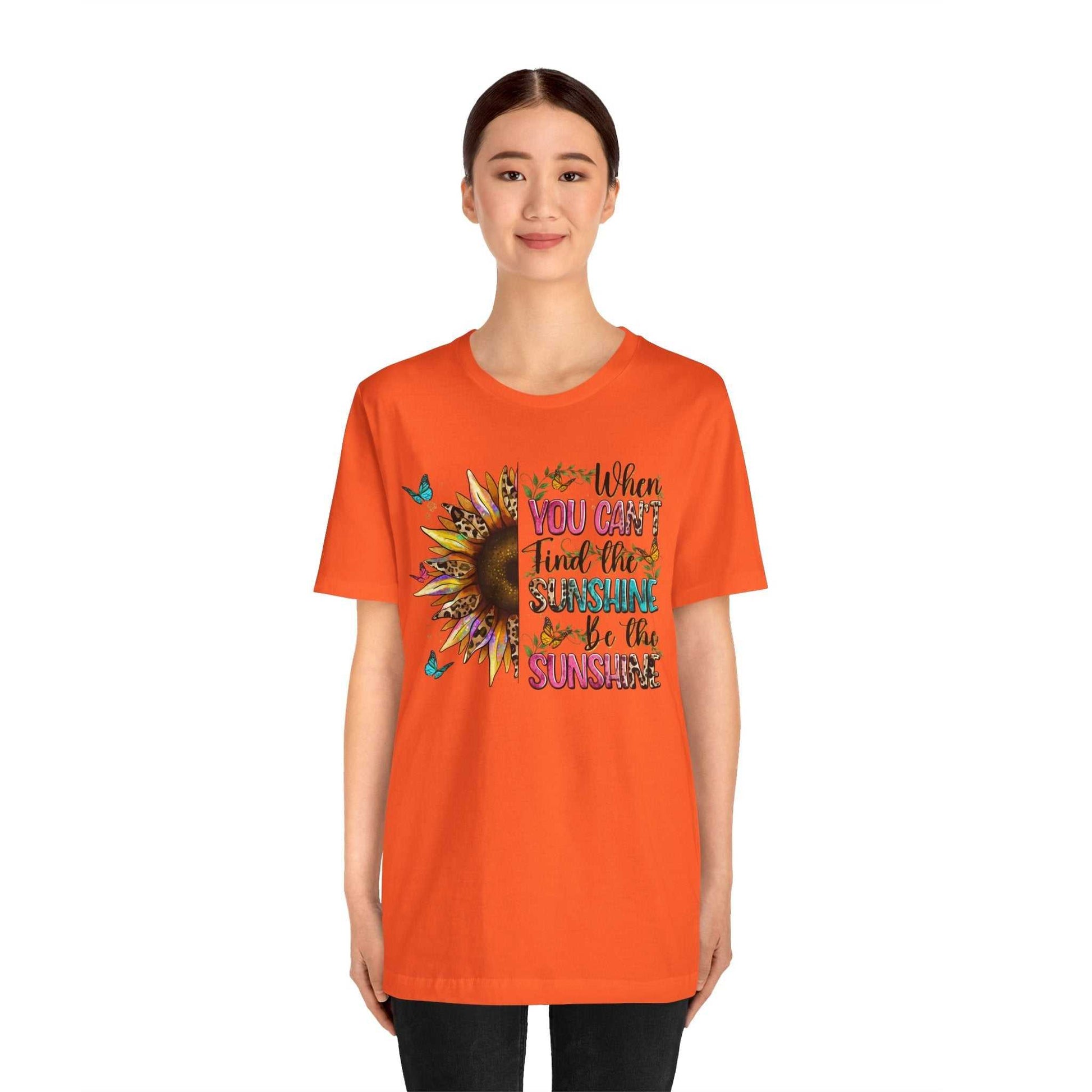 Woman wearing orange Sunshine Quote Tee with sunflower and inspirational quote design