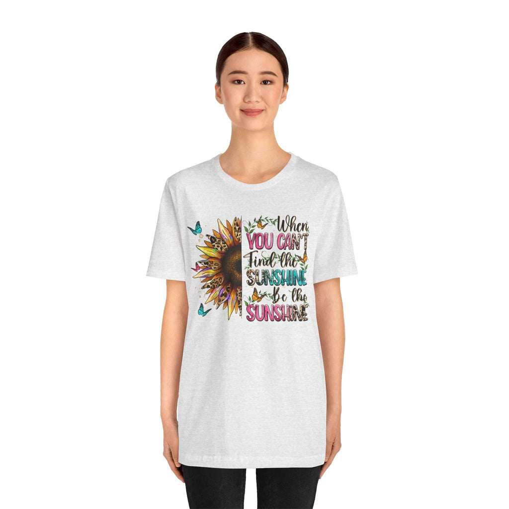 Woman wearing white Sunshine Quote Tee with colorful sunflower and text design reading "When you can't find the sunshine be the sunshine"