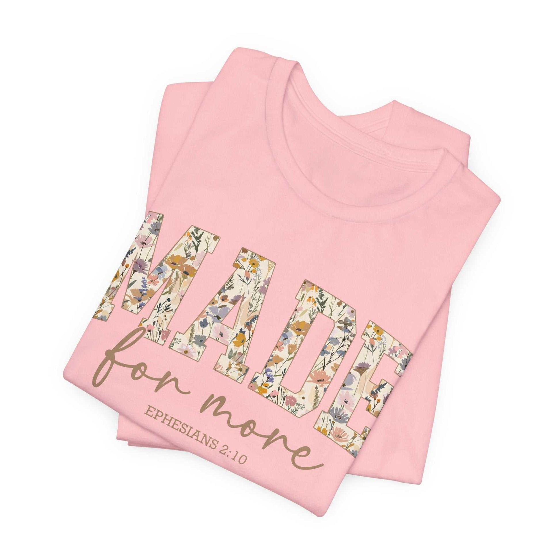 Pink folded Made for More Tee with floral patterned text and Ephesians 2:10 scripture verse design