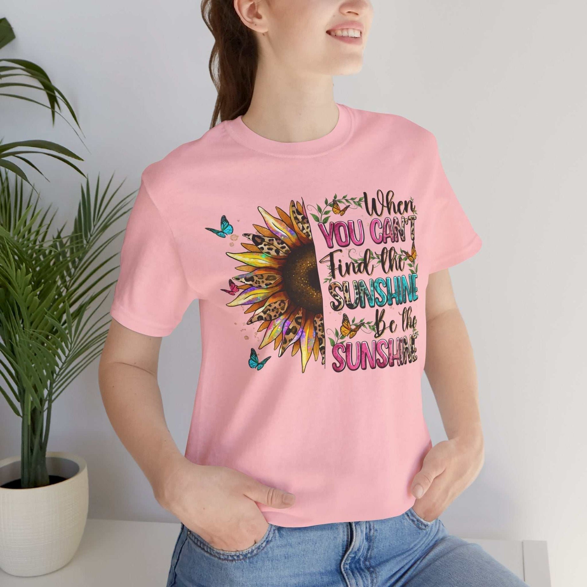 Woman wearing pink Sunshine Quote Tee with sunflower and motivational text design