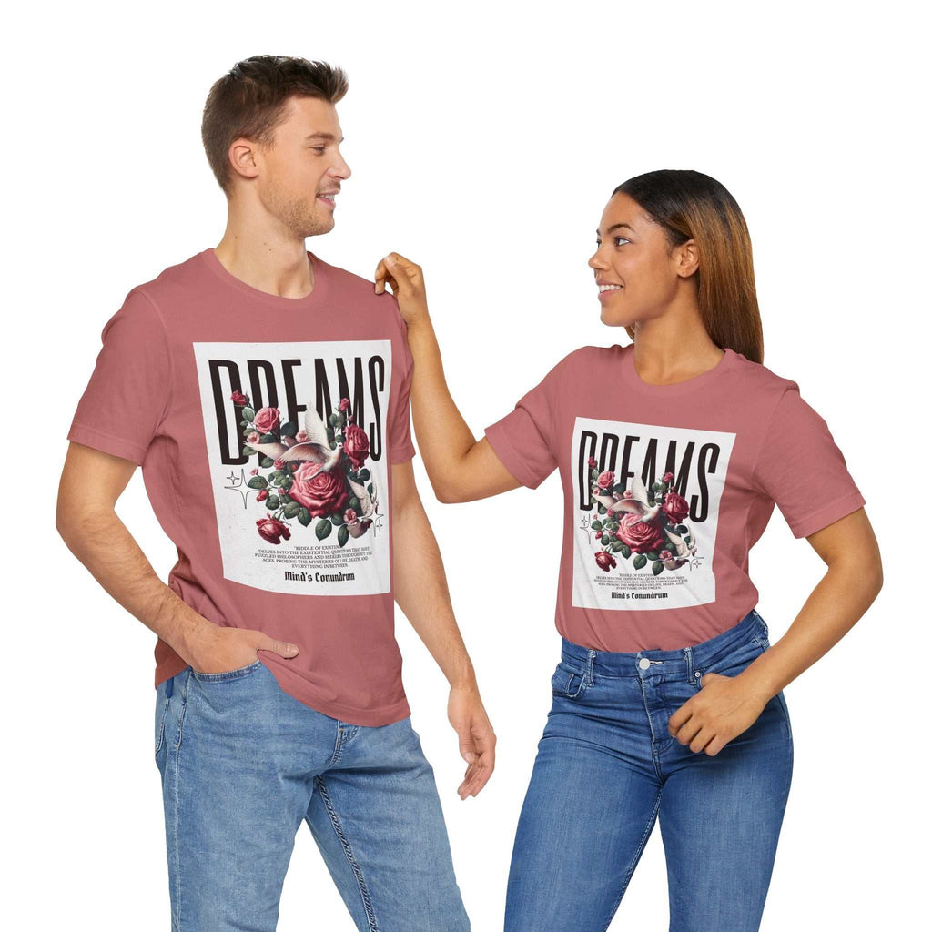 Unisex Dreams Floral Tee with pink background, bold typography, and floral graphic, worn casually by man and woman in jeans.