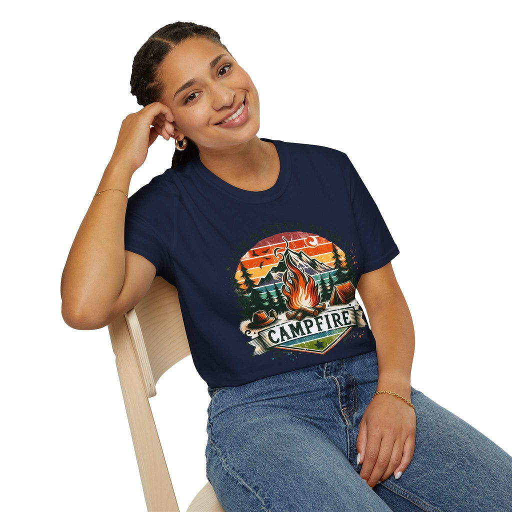 Woman wearing navy camping adventure unisex t-shirt with colorful campfire design sitting on chair
