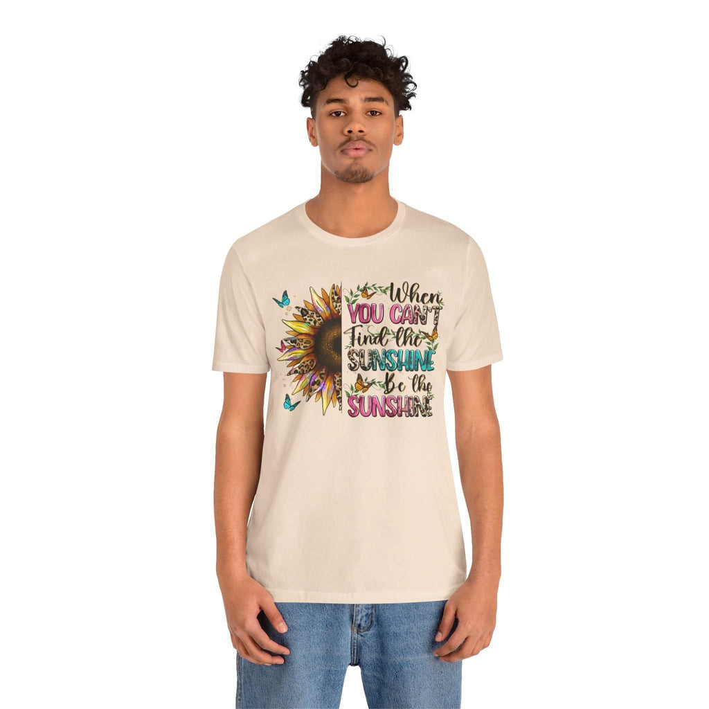 Man wearing beige Sunshine Quote Tee with colorful sunflower and motivational text design on front