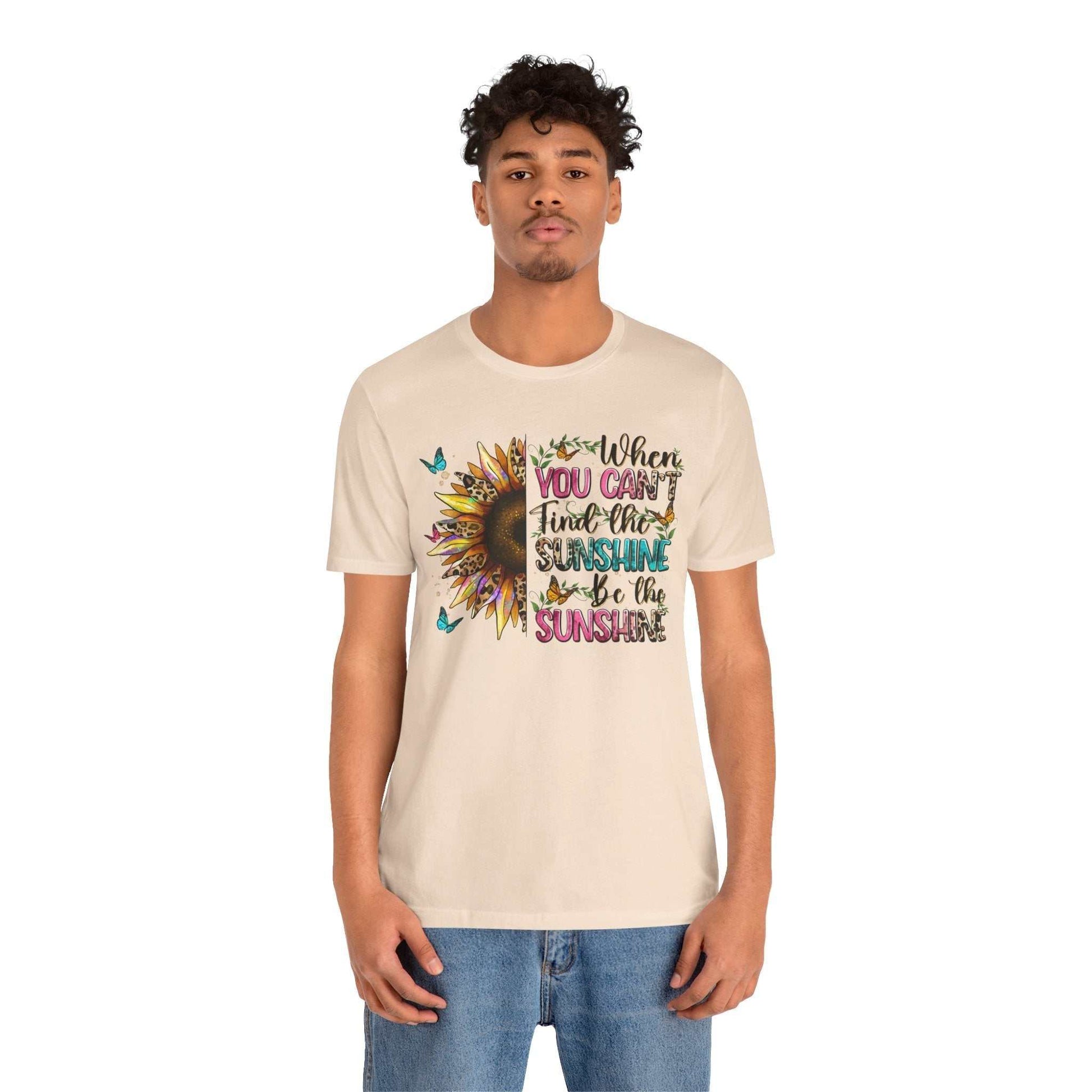 Man wearing beige Sunshine Quote Tee with colorful sunflower and motivational text design on front