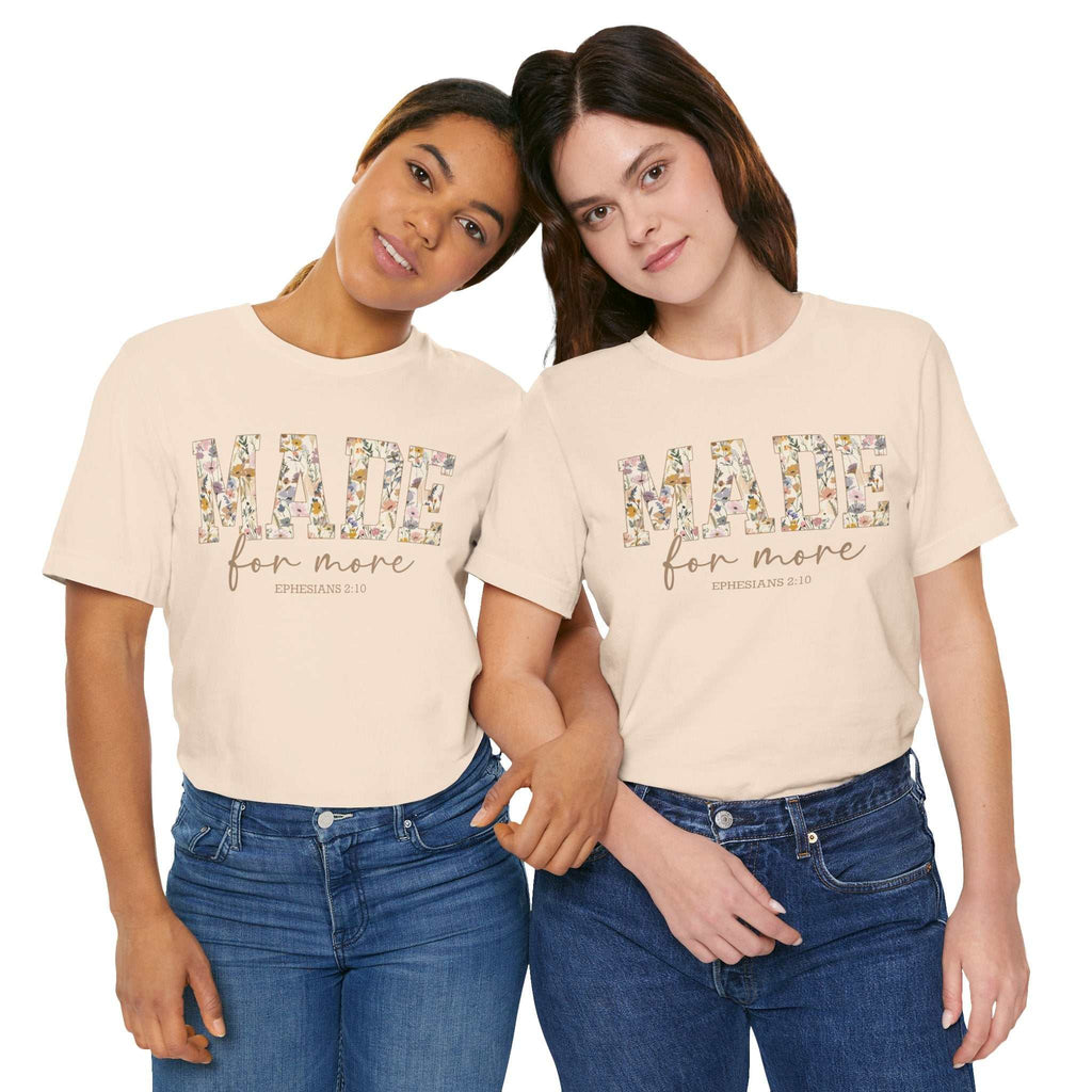 Two women wearing beige "Made for More" unisex short sleeve tees with floral print lettering, styled casually with jeans.