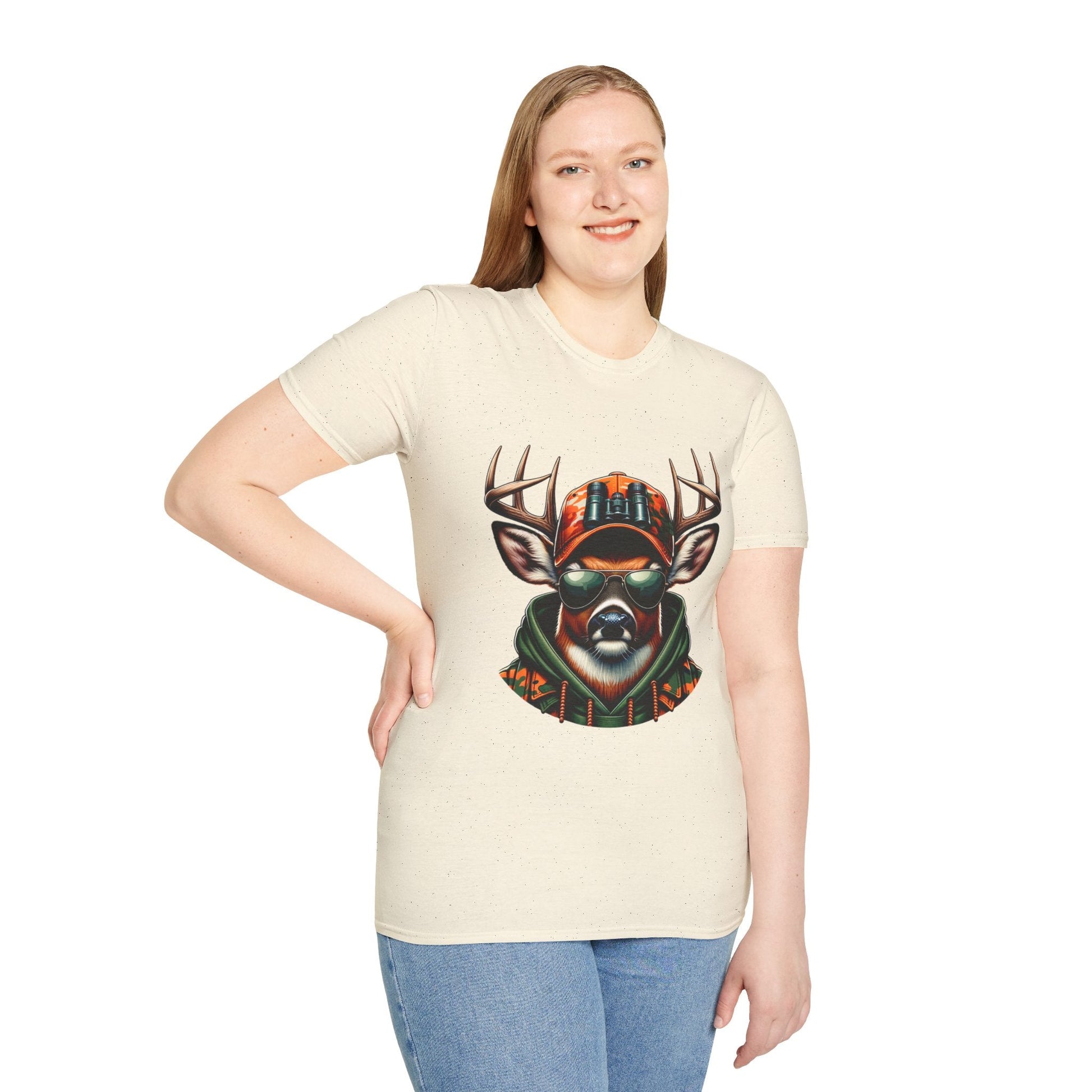 Woman wearing a soft beige Hunting Enthusiast T-Shirt with a graphic of a deer wearing sunglasses and a hat, paired with blue jeans.