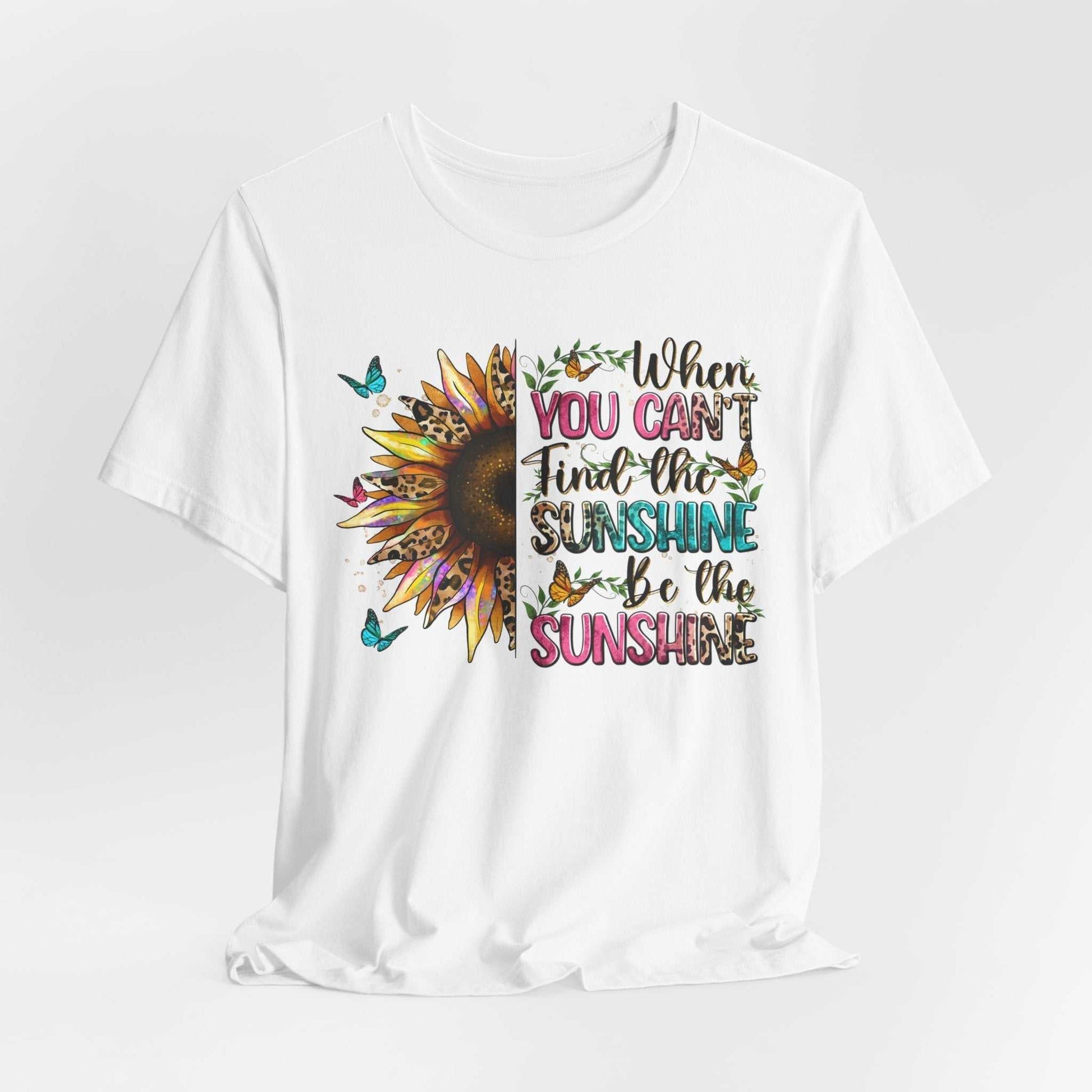 White unisex tee with colorful sunflower and butterfly graphic and "When you can't find the sunshine, be the sunshine" quote design