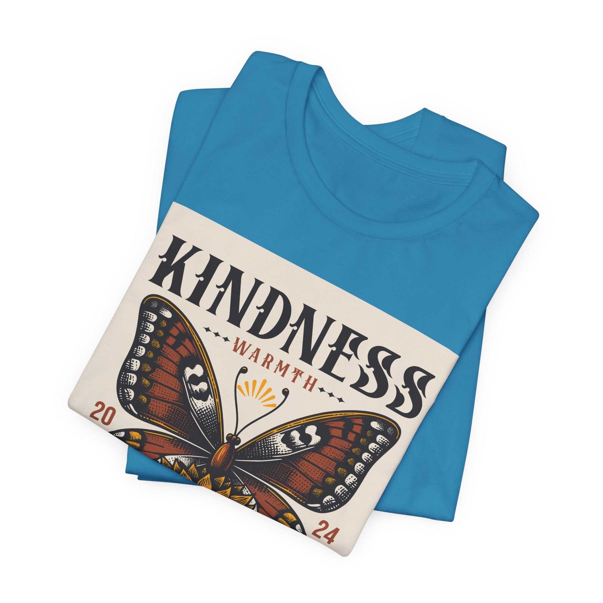 Folded blue Kindness Butterfly Tee with a butterfly and sunflower design and "KINDNESS" text on the front