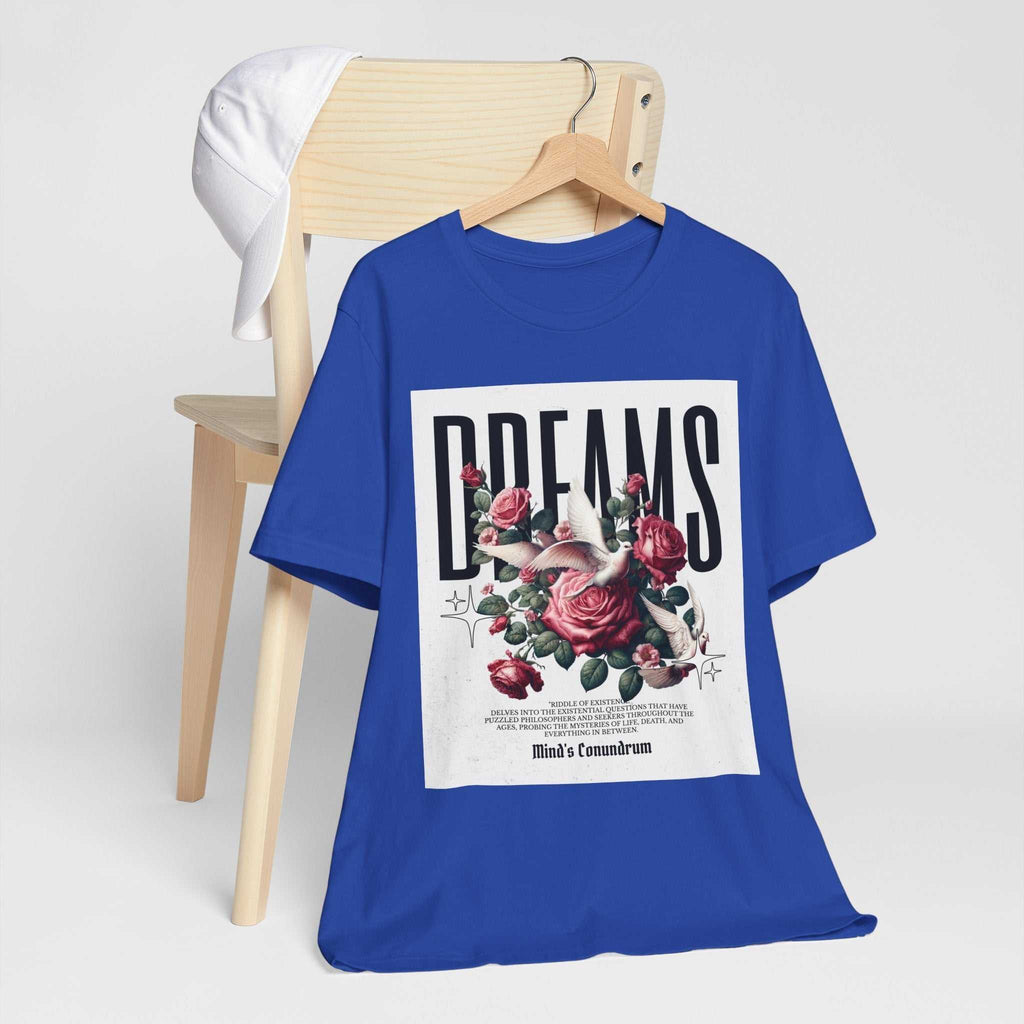 Blue Dreams Floral Tee with bold typography and pink rose graphic on front displayed on a wooden chair with white baseball cap