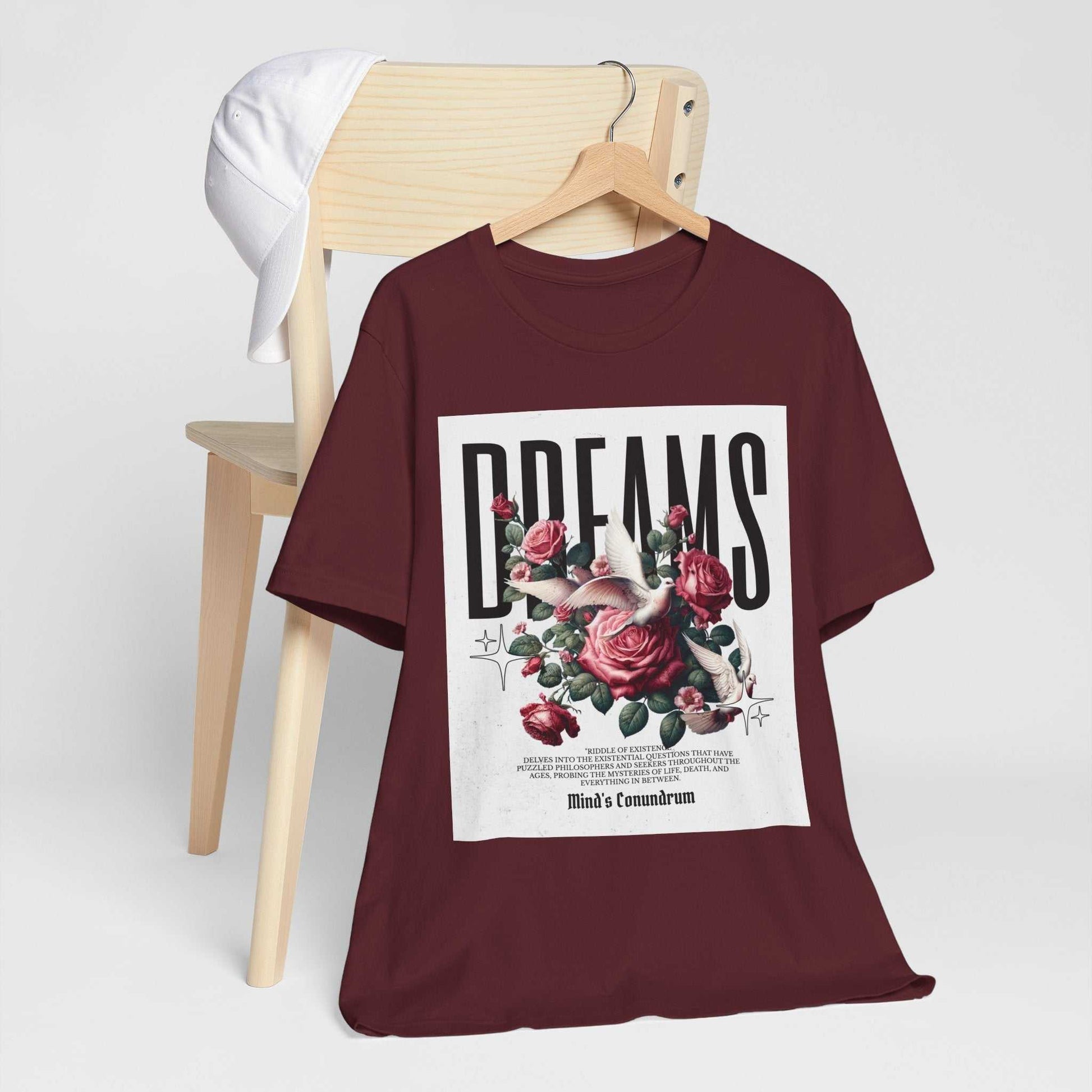 Maroon Dreams Floral Tee with bold typography and rose flower design displayed on a wooden hanger.