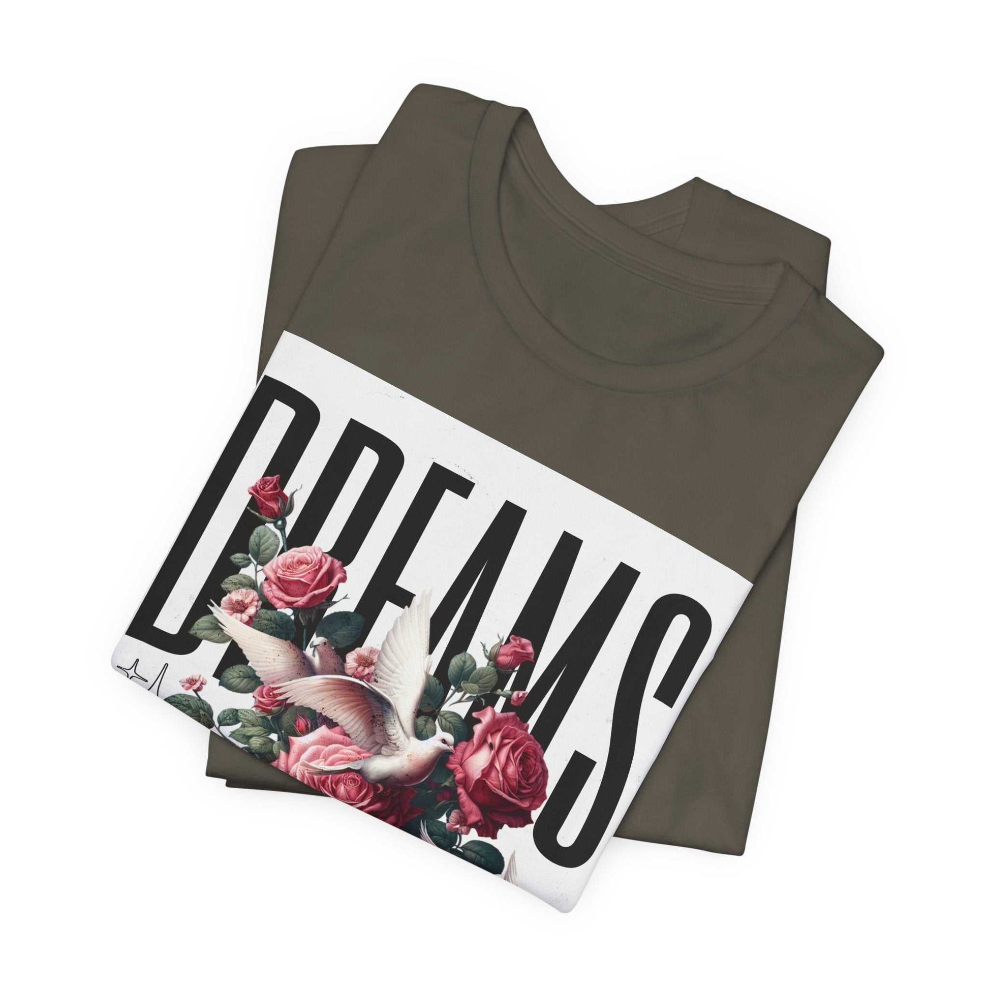 Folded dark gray t-shirt with a large white graphic featuring the word "DREAMS" in bold letters, decorated with pink roses and a white dove floral design.