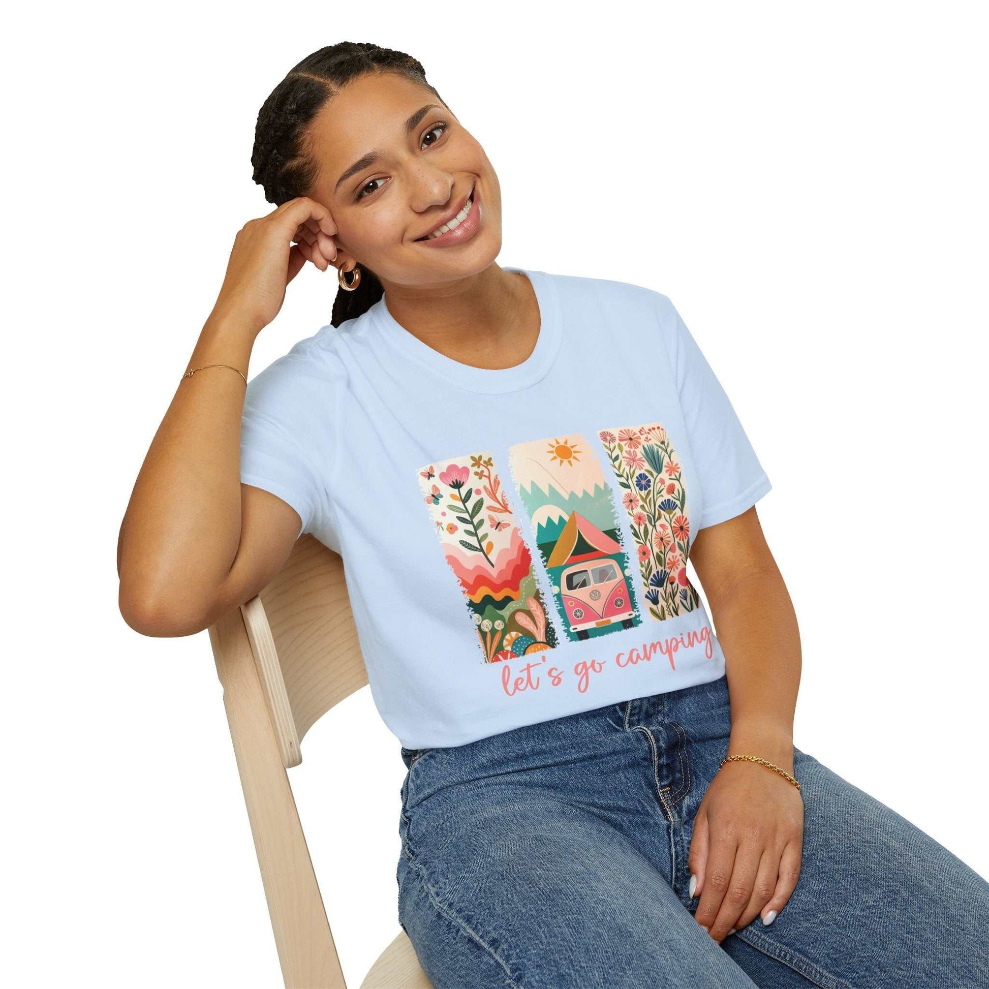 Woman wearing a light blue Camping Adventure unisex softstyle t-shirt with colorful outdoor-themed graphic and "let's go camping" text.