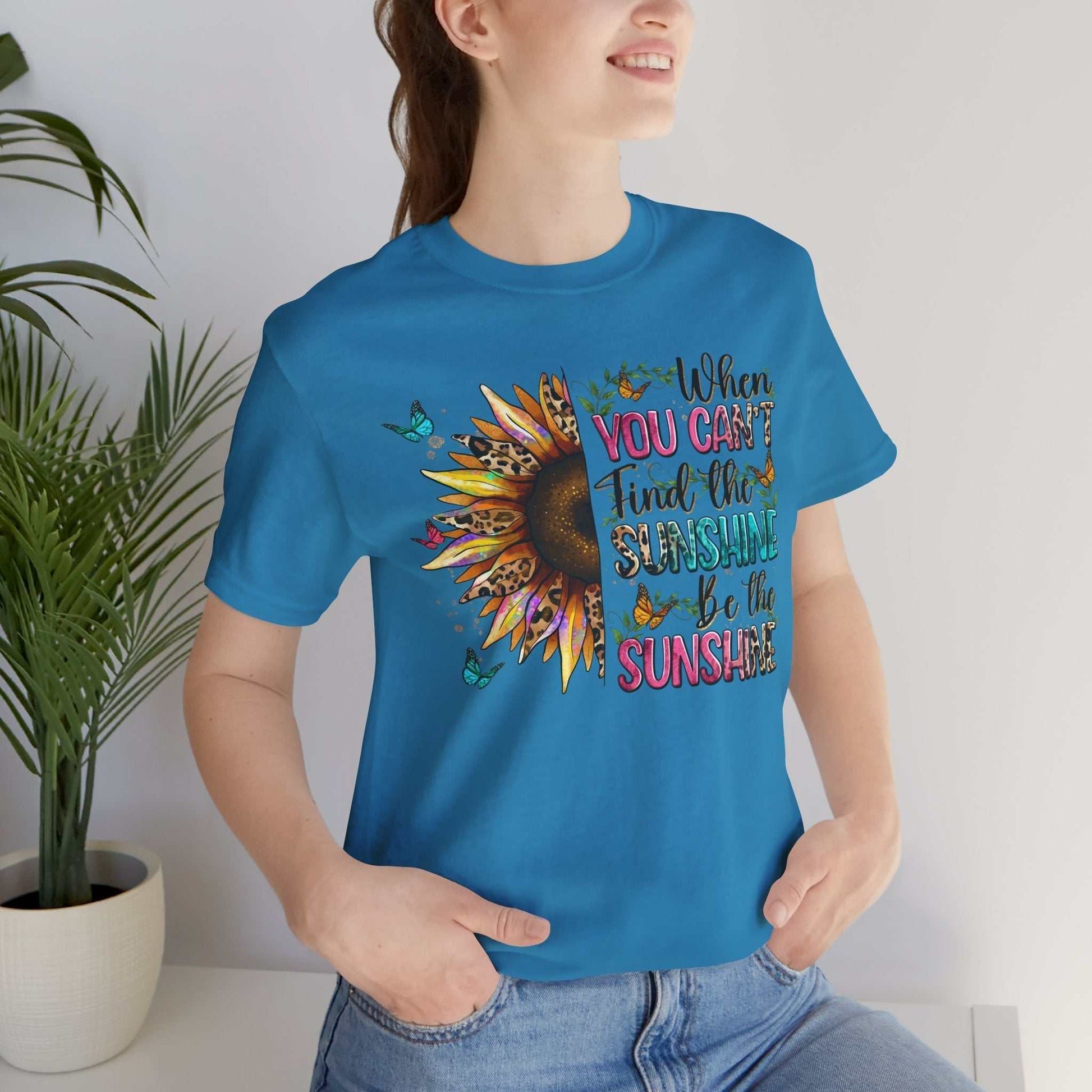 Woman wearing blue Sunshine Quote Tee with sunflower and inspirational text design