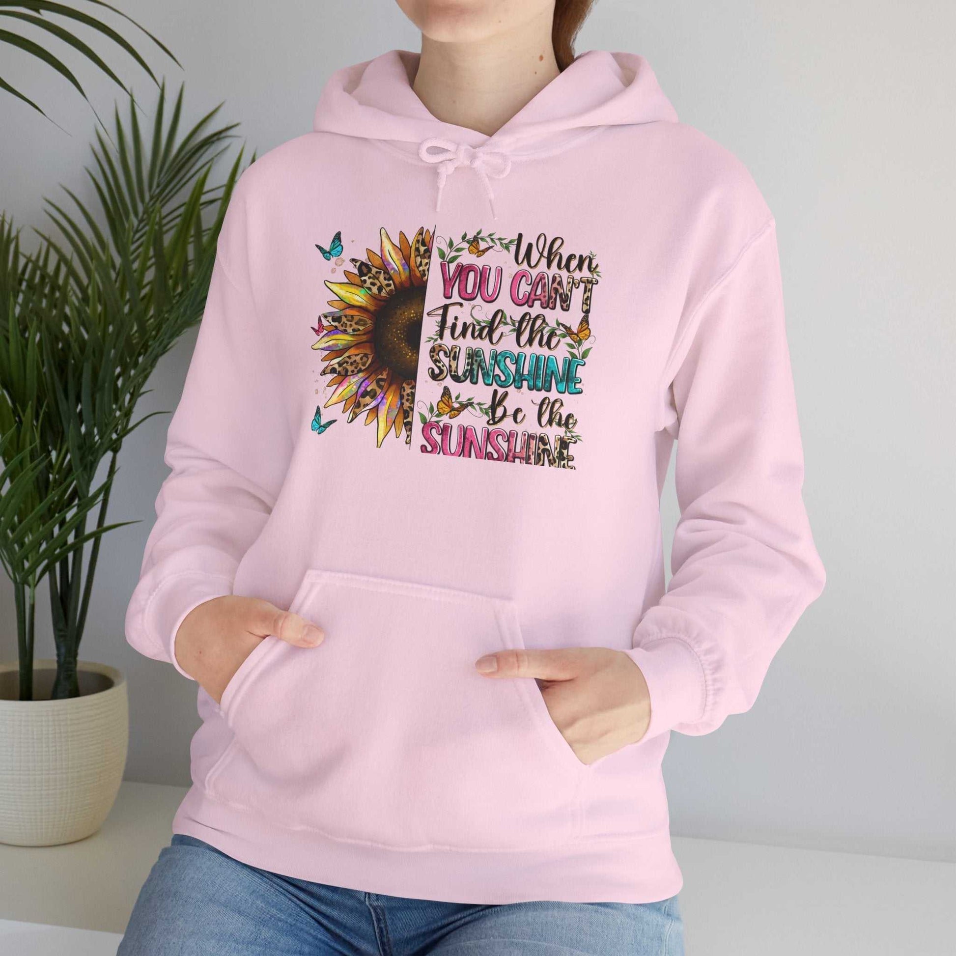 Woman wearing a pink sunflower quote hoodie with colorful inspirational text and butterflies, featuring a kangaroo pocket and adjustable hood.