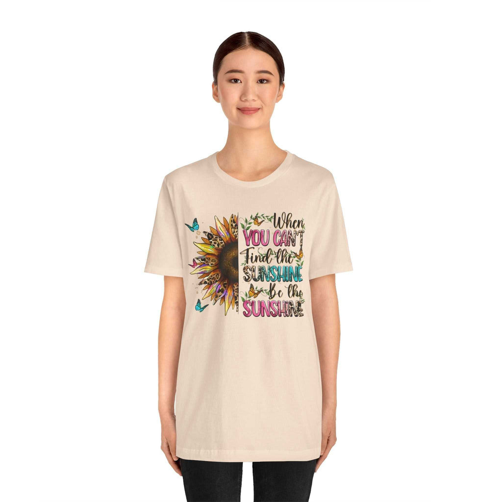 Woman wearing beige Sunshine Quote Tee with colorful sunflower and motivational text design