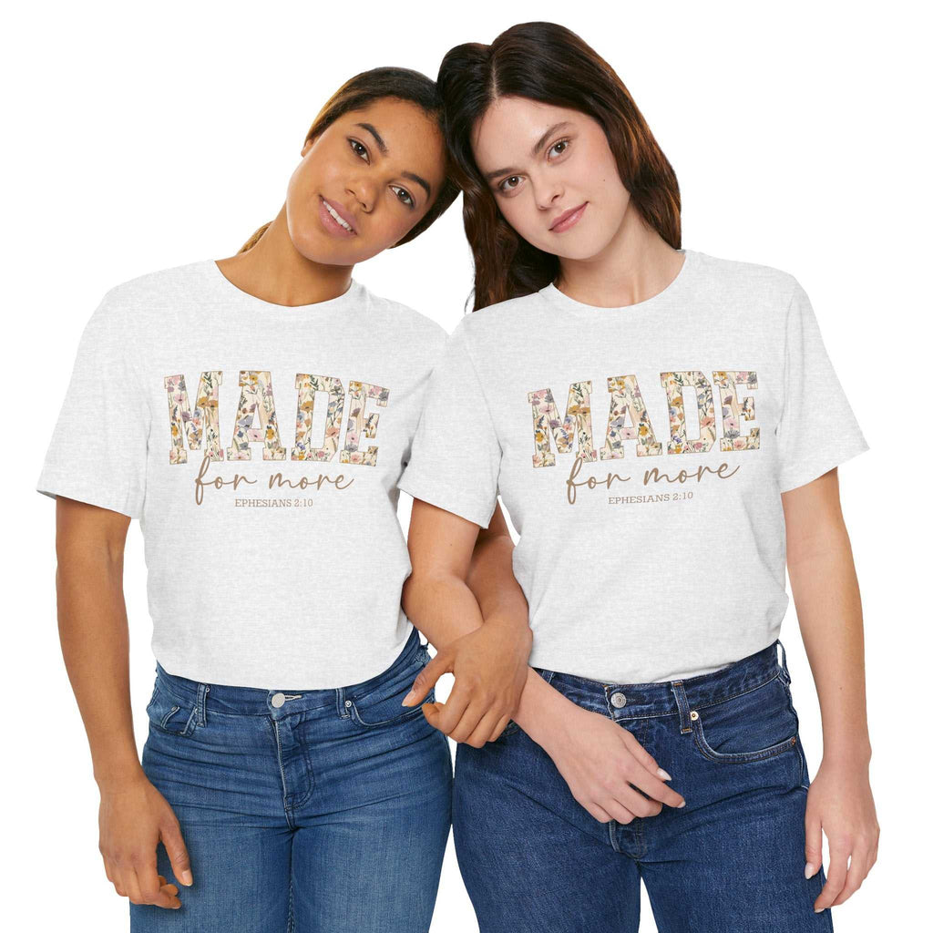 Two women wearing white Made for More Tee shirts with floral print text and jeans, casual unisex style