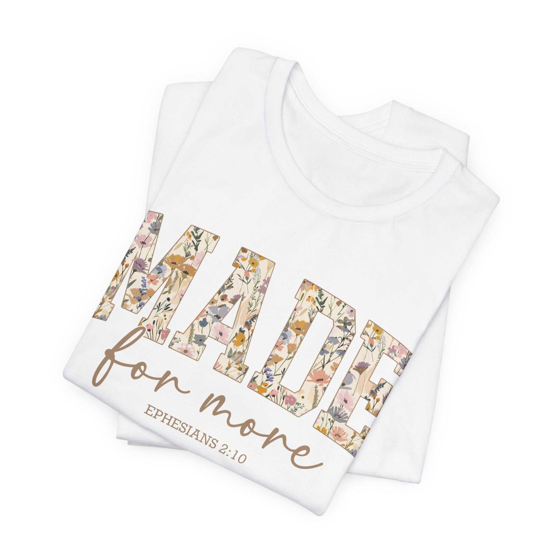 White "Made for More Tee" with floral patterned lettering and Ephesians 2:10 scripture printed on front, folded and stacked