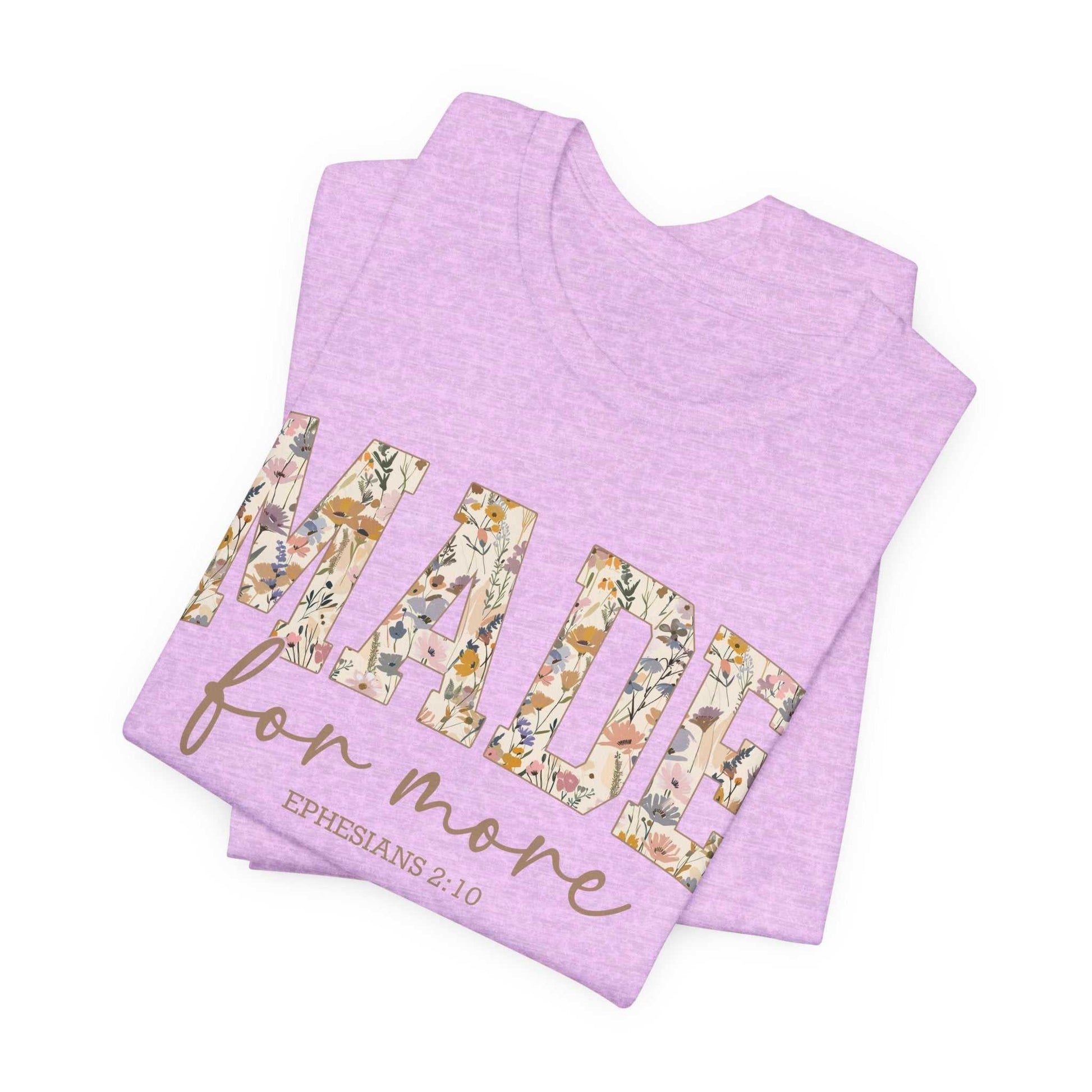 Folded lavender Made for More Tee with floral patterned text and scripture reference Ephesians 2:10 on front