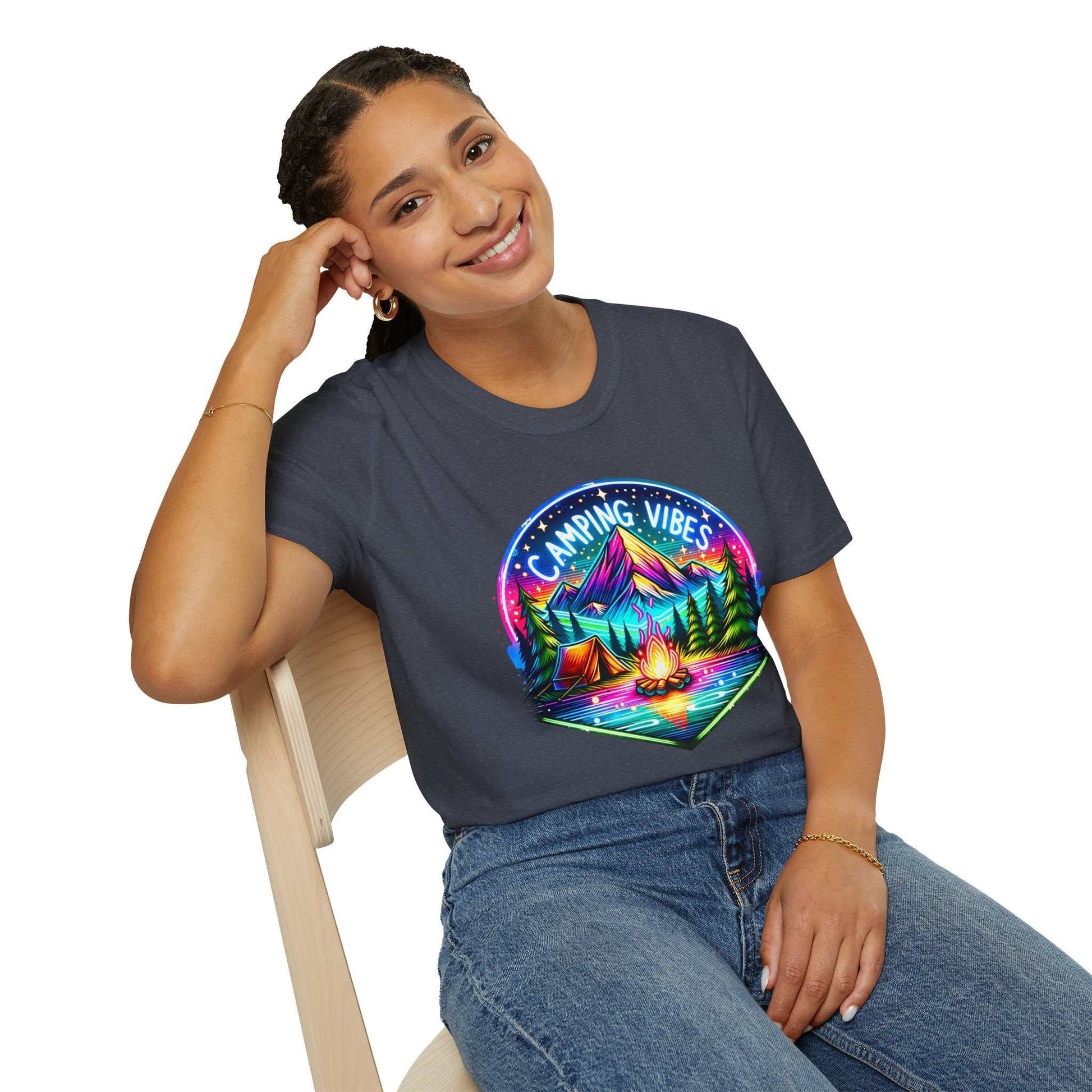 Woman wearing a navy Camping Vibes Unisex Softstyle T-shirt with colorful camping graphic sitting on a chair