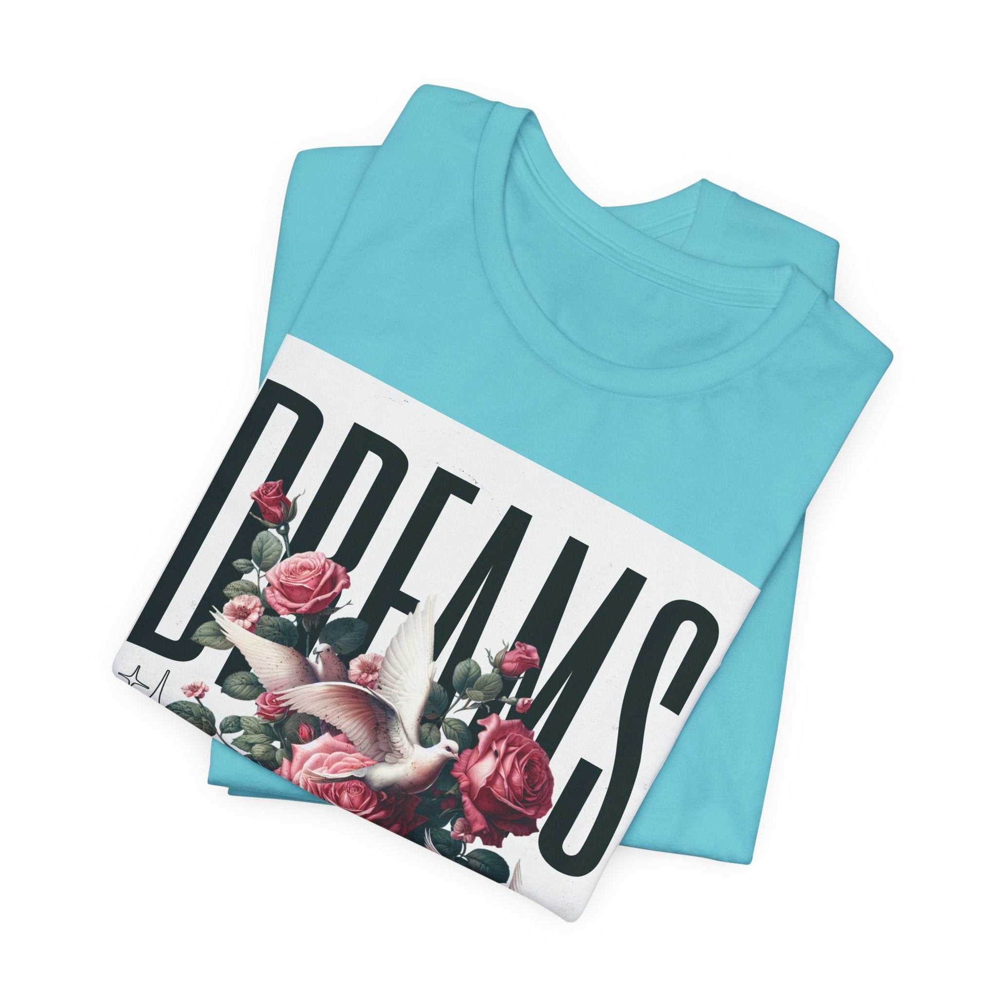 Folded light blue Dreams Floral Tee with bold typography and floral and bird design on front
