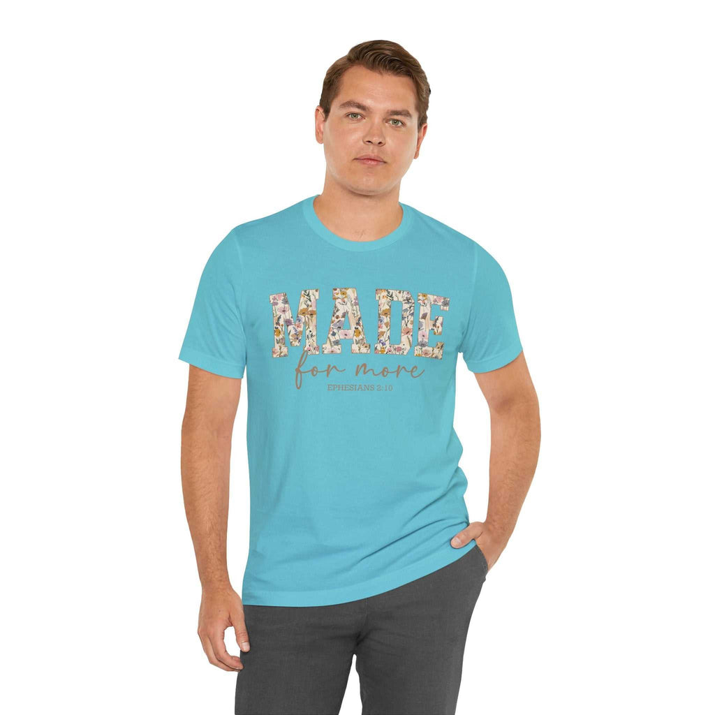 Man wearing a light blue "Made for More" floral print unisex short sleeve tee and dark pants standing against white background