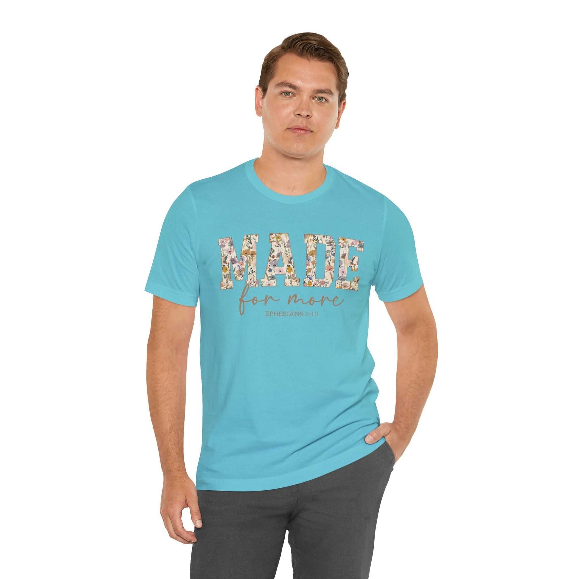 Man wearing a light blue "Made for More" floral print unisex short sleeve tee and dark pants standing against white background
