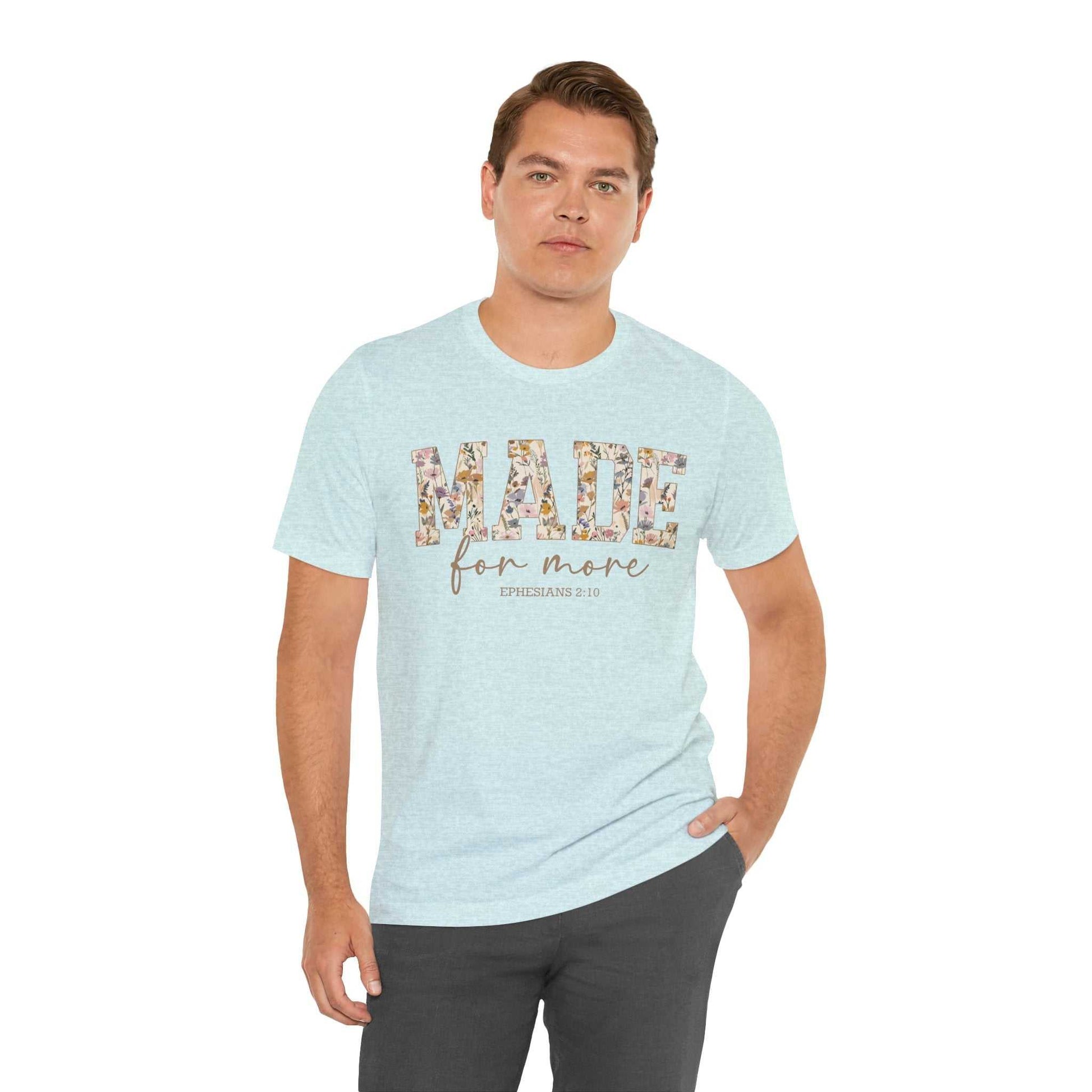 Man wearing light blue Made for More Tee with floral print text on front, paired with dark pants
