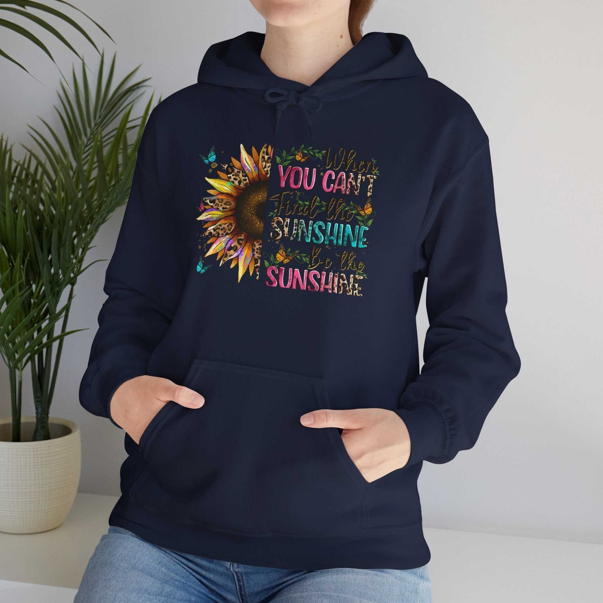 Woman wearing navy sunflower quote hoodie with colorful inspirational text and front pocket