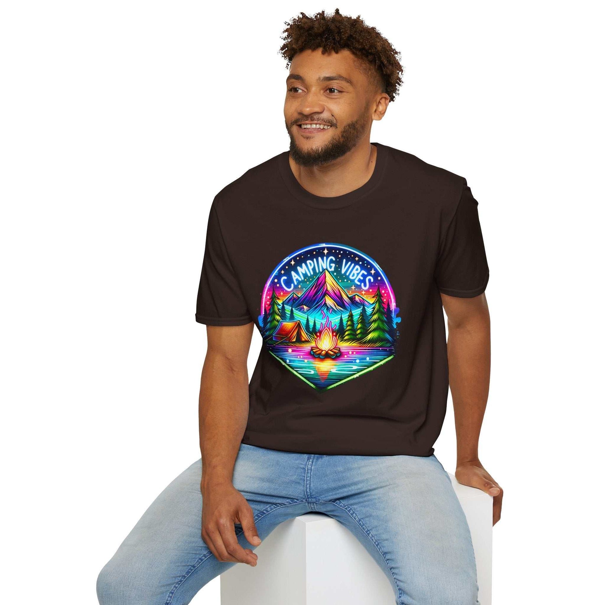Man wearing black Camping Vibes Unisex Softstyle T-Shirt with colorful camping graphic sitting on white block