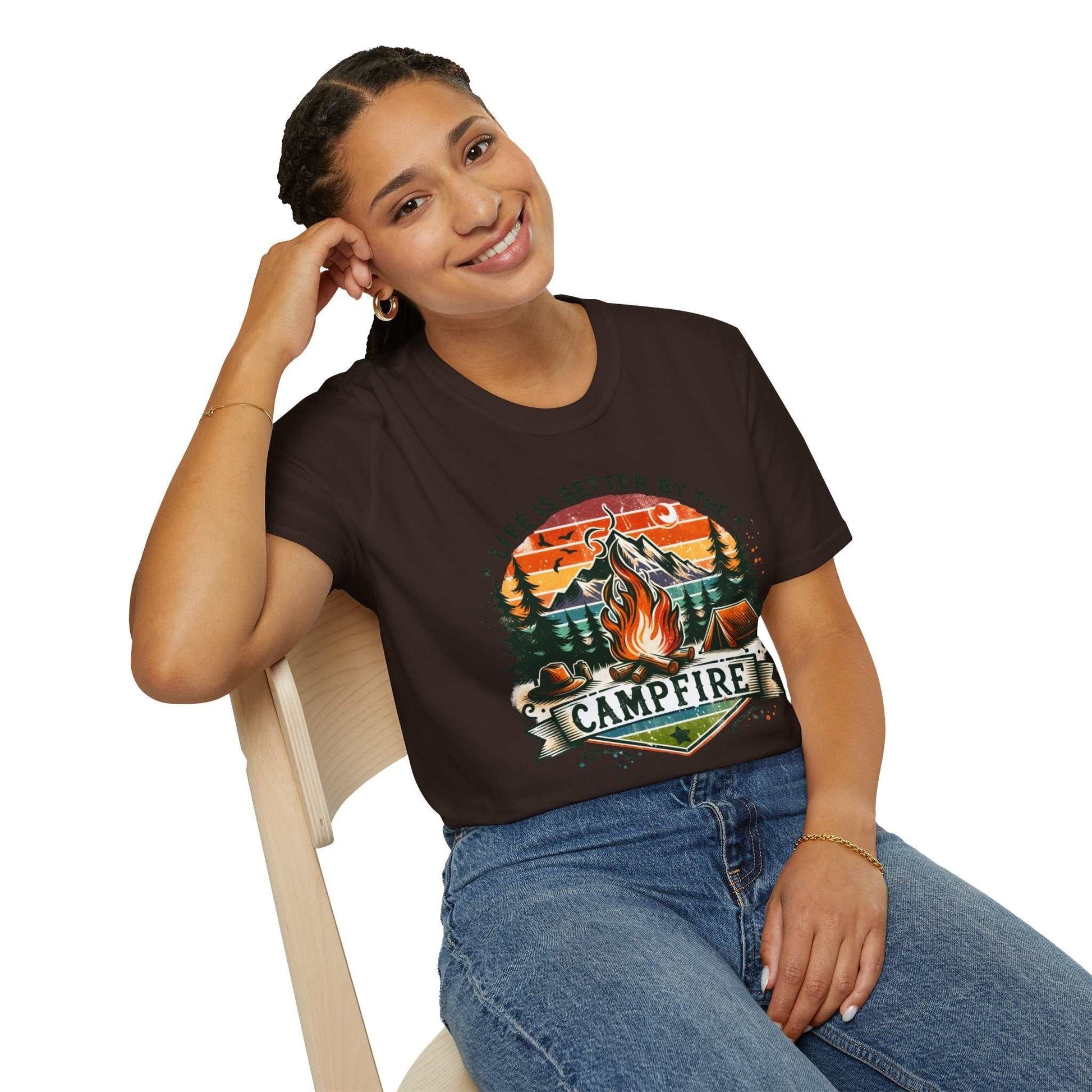 Woman wearing black unisex Camping Adventure T-shirt with campfire graphic and mountain design sitting on chair